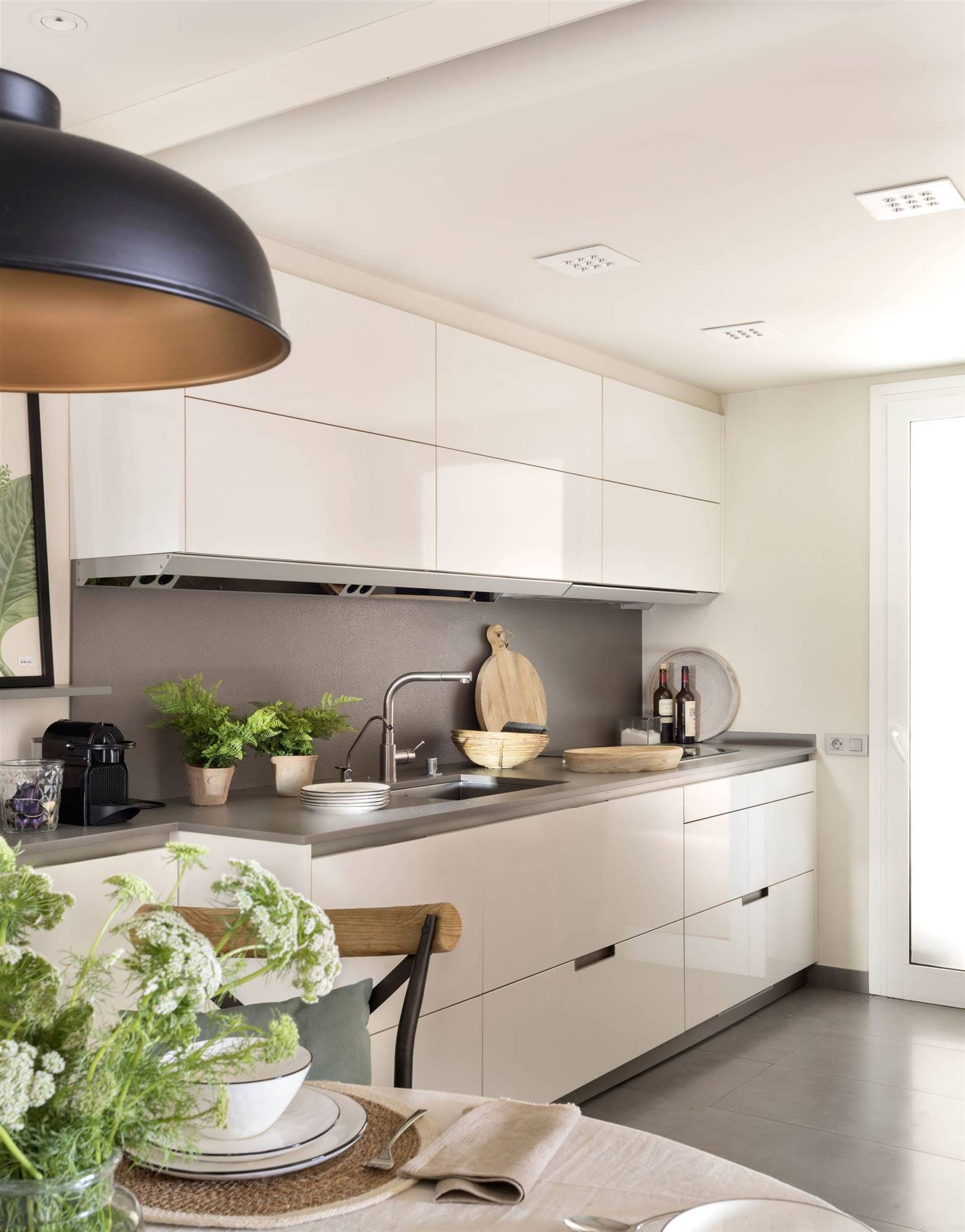 Moderna cocina con mobiliario de color blanco y encimera en gris. 