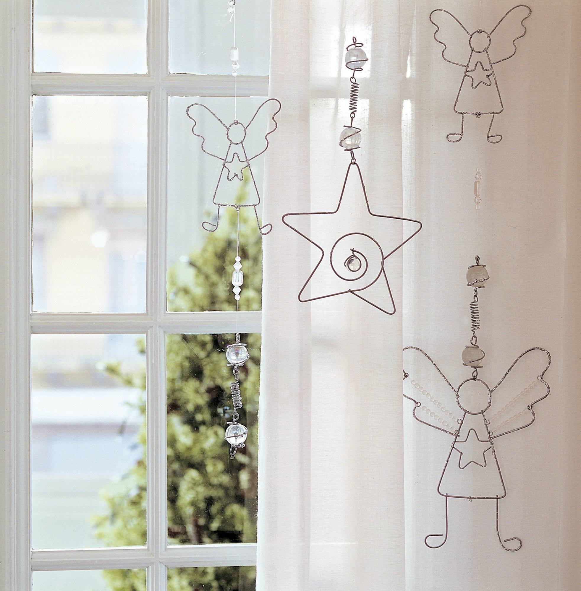 Detalle decorativo de guirnalda de ángeles hecha de alambre para vestir la ventana.