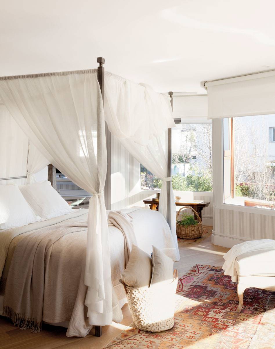 Dormitorio con dosel con cortinas blancas. 