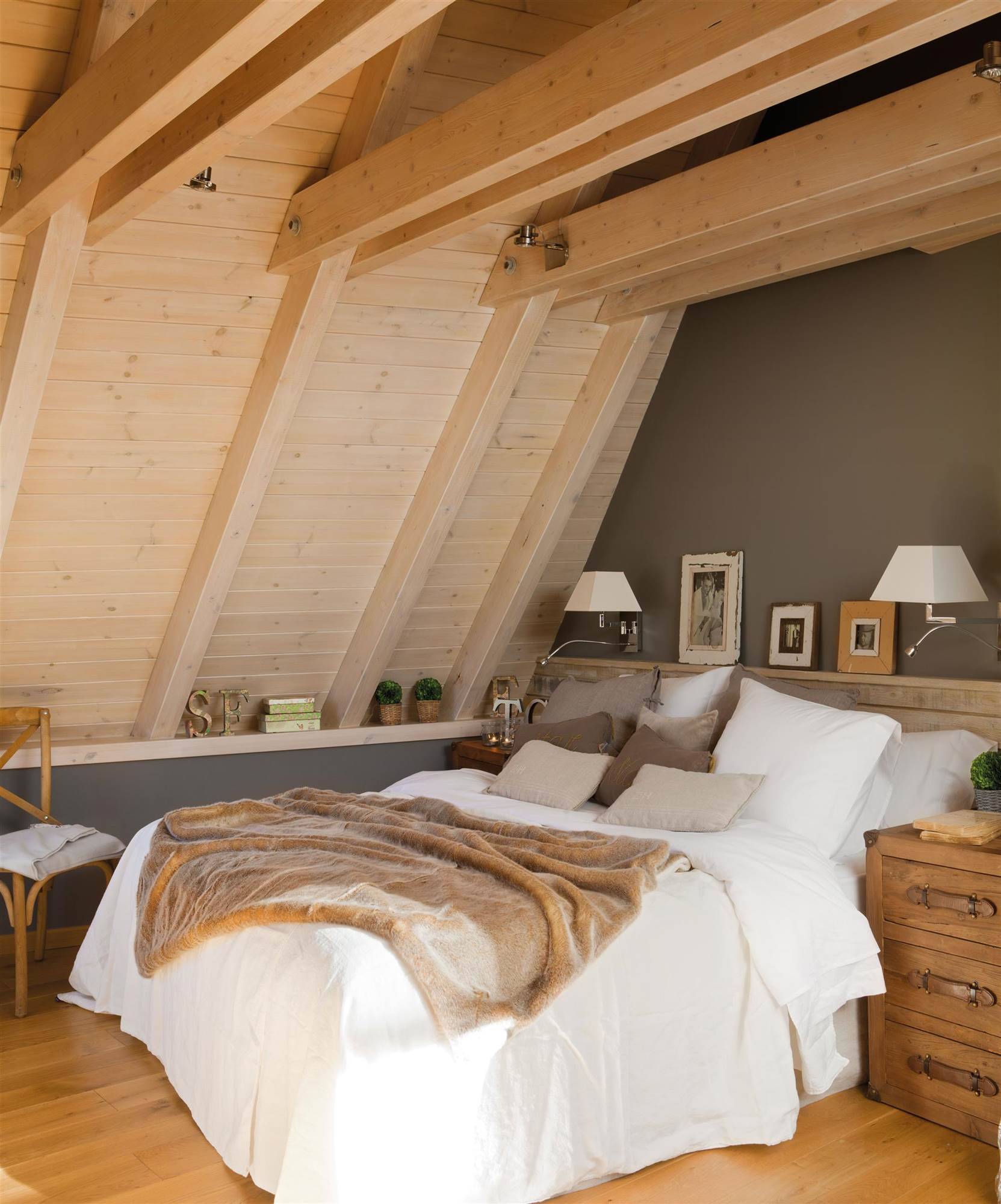 Dormitorio con paredes de madera y ropa de cama blanca. 