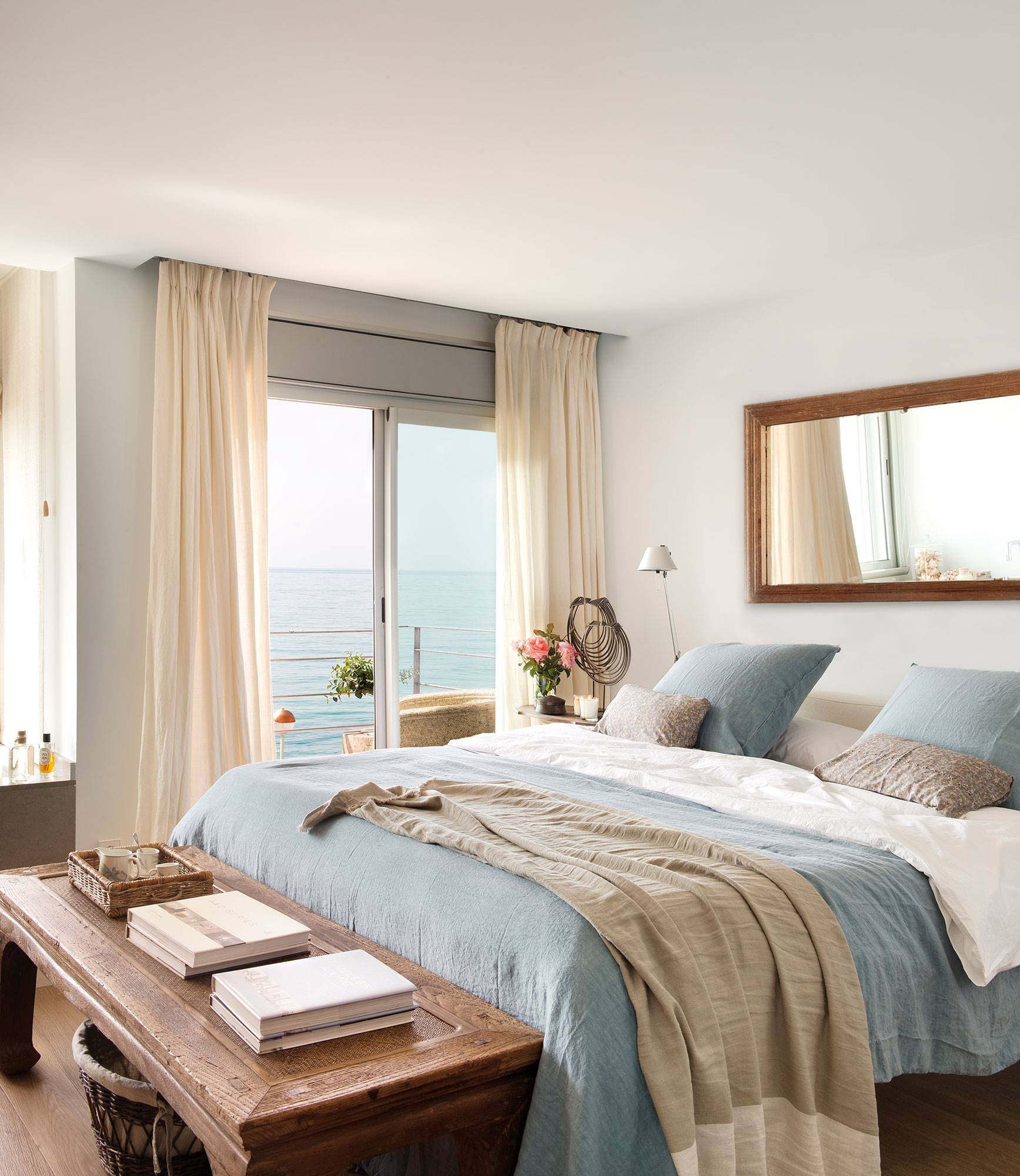Dormitorio con ropa de cama blanca, azul y beige. 