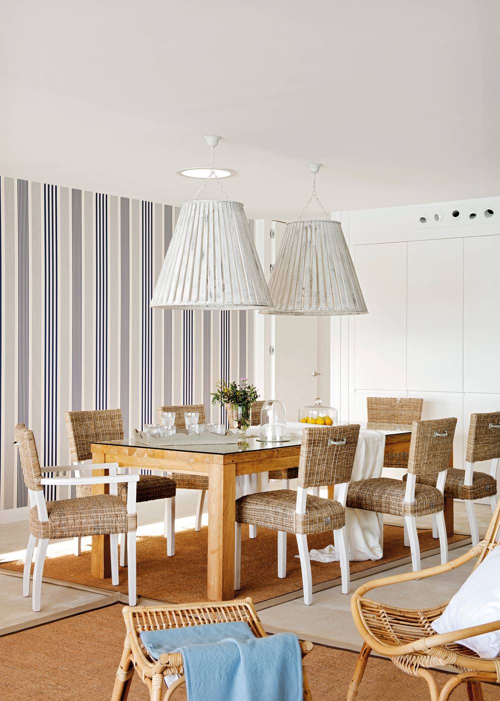 Comedor de apartamento de verano con papel pintado a rayas azules y mesa con sobre de madera