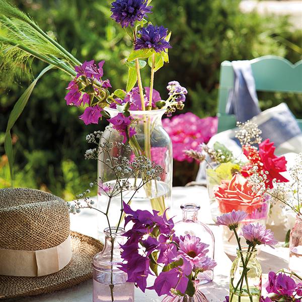 Diferentes jarrones con flores sobre mesa de exterior