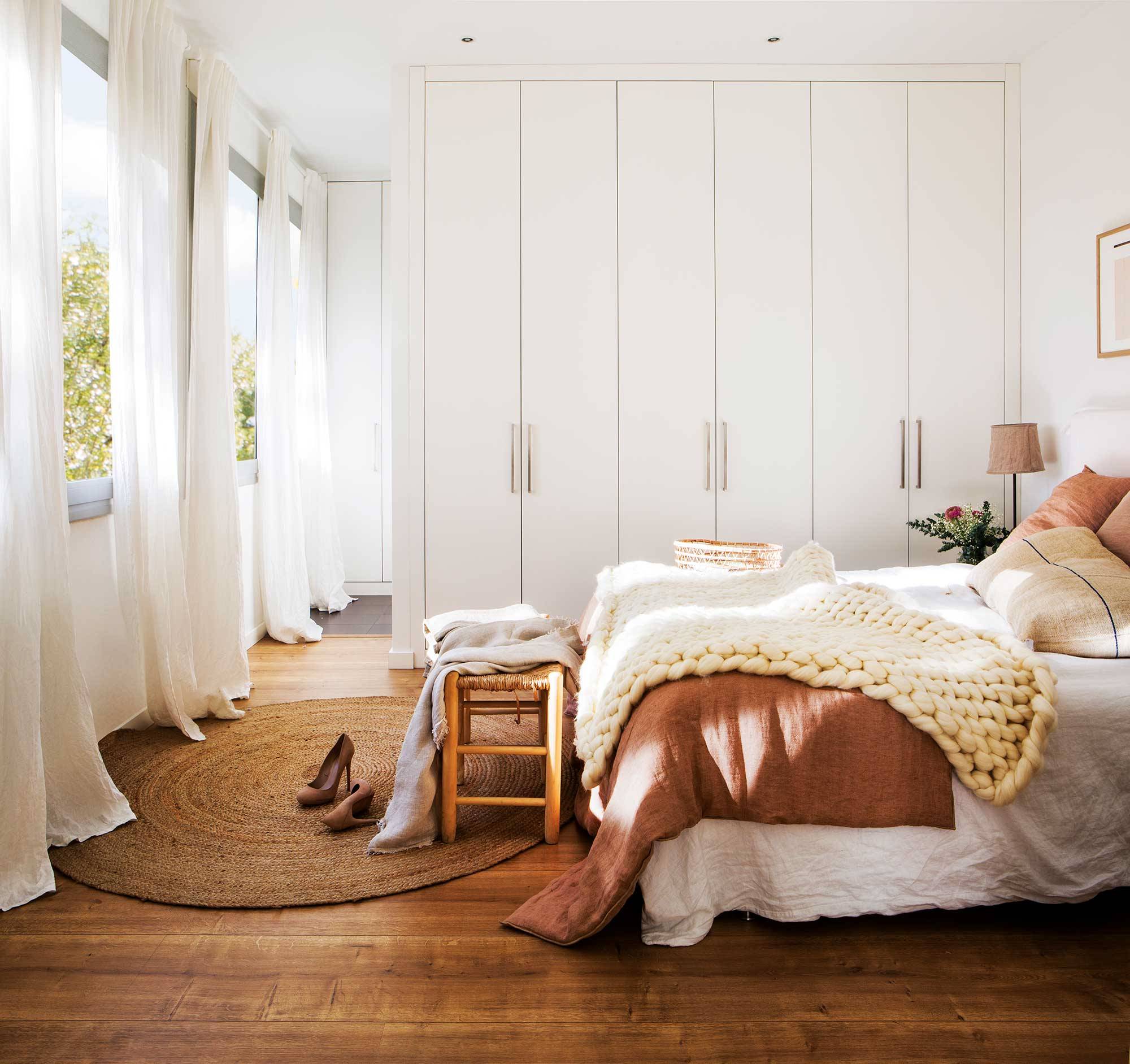 Dormitorio con armario blanco y ropa de cama blanca y rosa. 