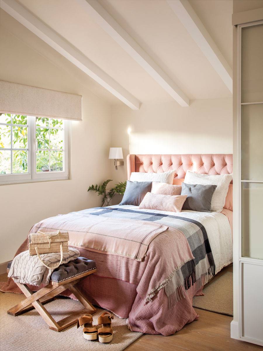 Dormitorio abuhardillado con cabecero de capitoné en rosa. 