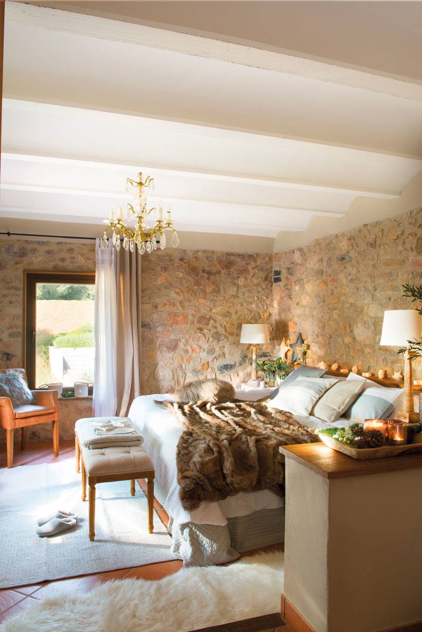 Dormitorio con paredes de piedra y lámpara de araña. 