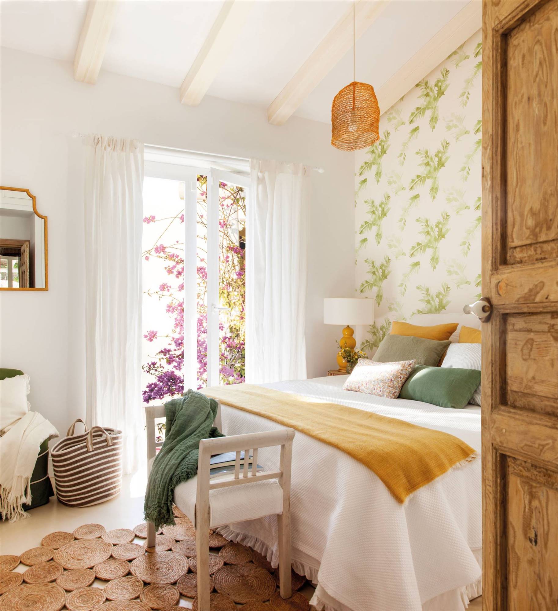 Dormitorio de primavera con papel pintado vegetal en la pared del cabecero y alfombra de fibra.