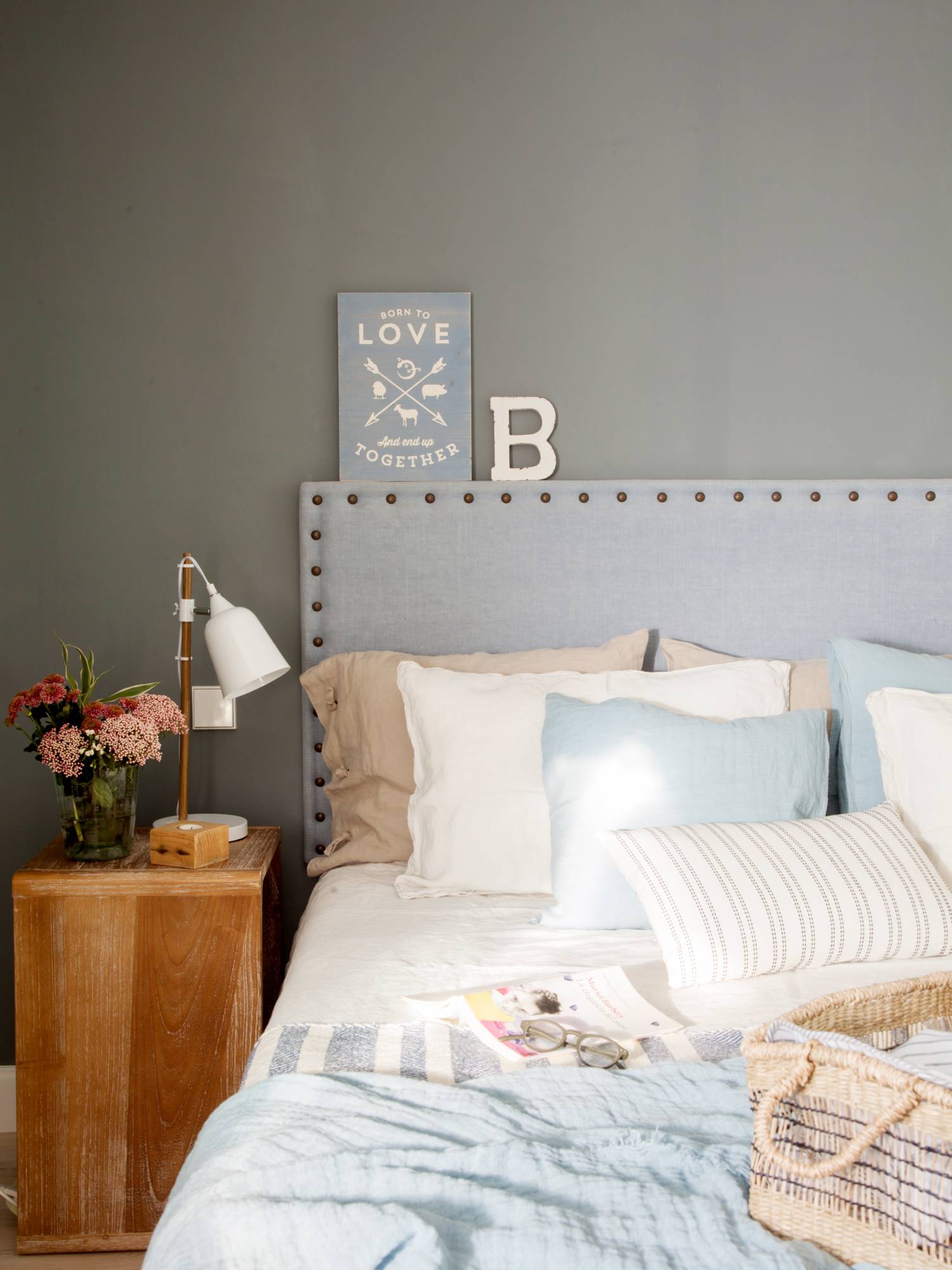 Dormitorio de primavera con pared gris y cabecero de tachuelas también en gris.