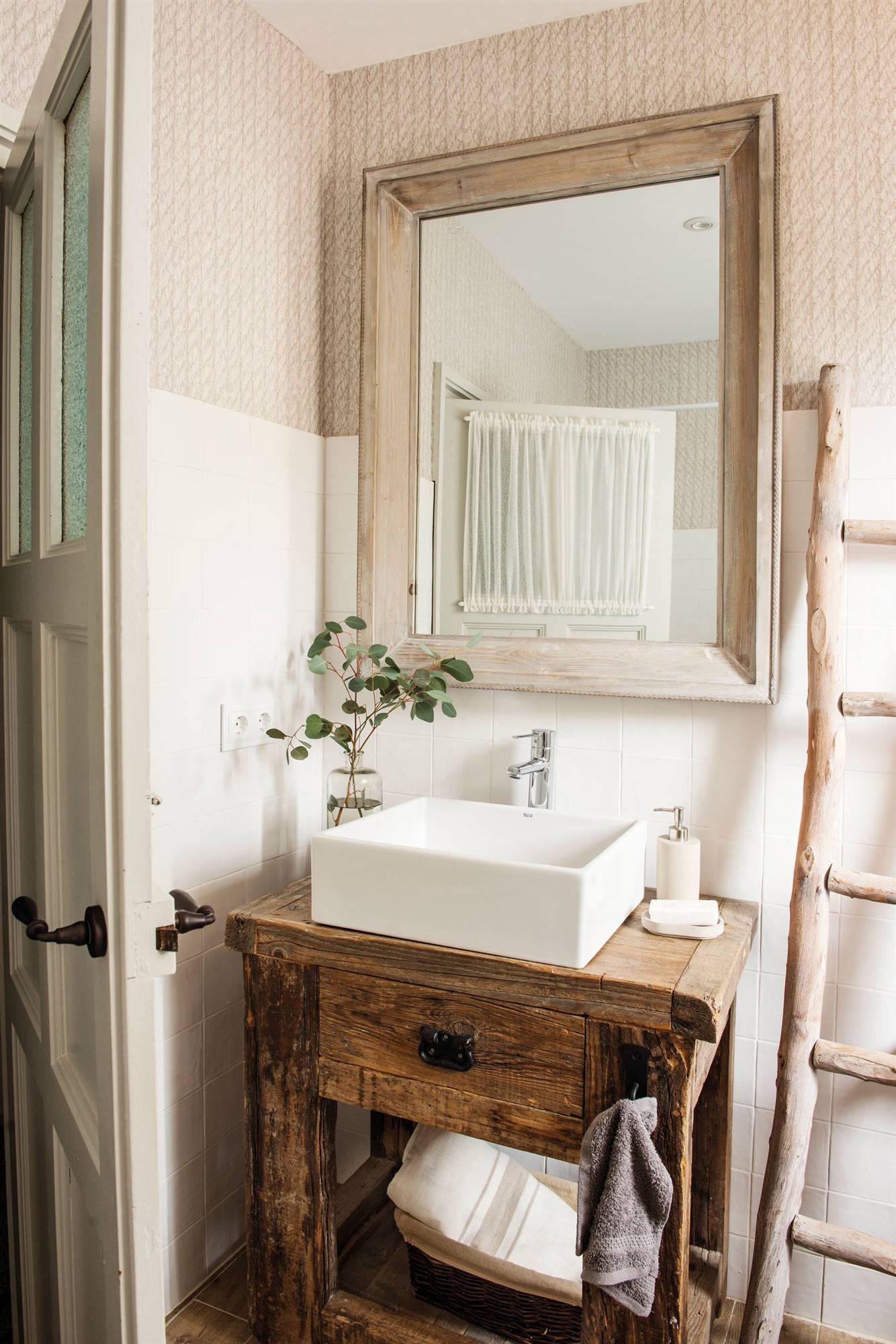 Baño pequeño con mueble bajolavabo rústico y paredes con papel pintado. 