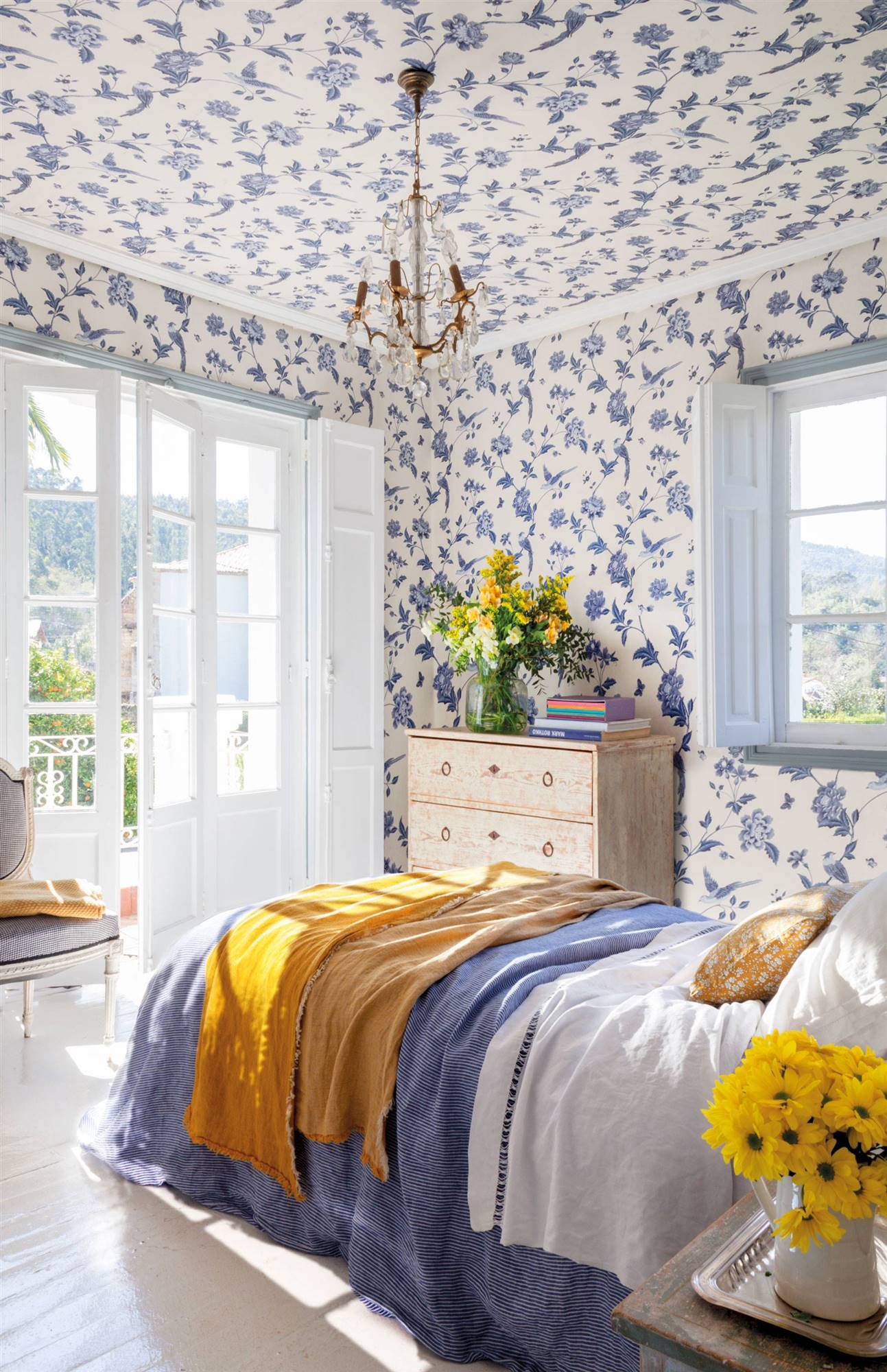 Dormitorio con papel pintado de flores azules incluso en el techo