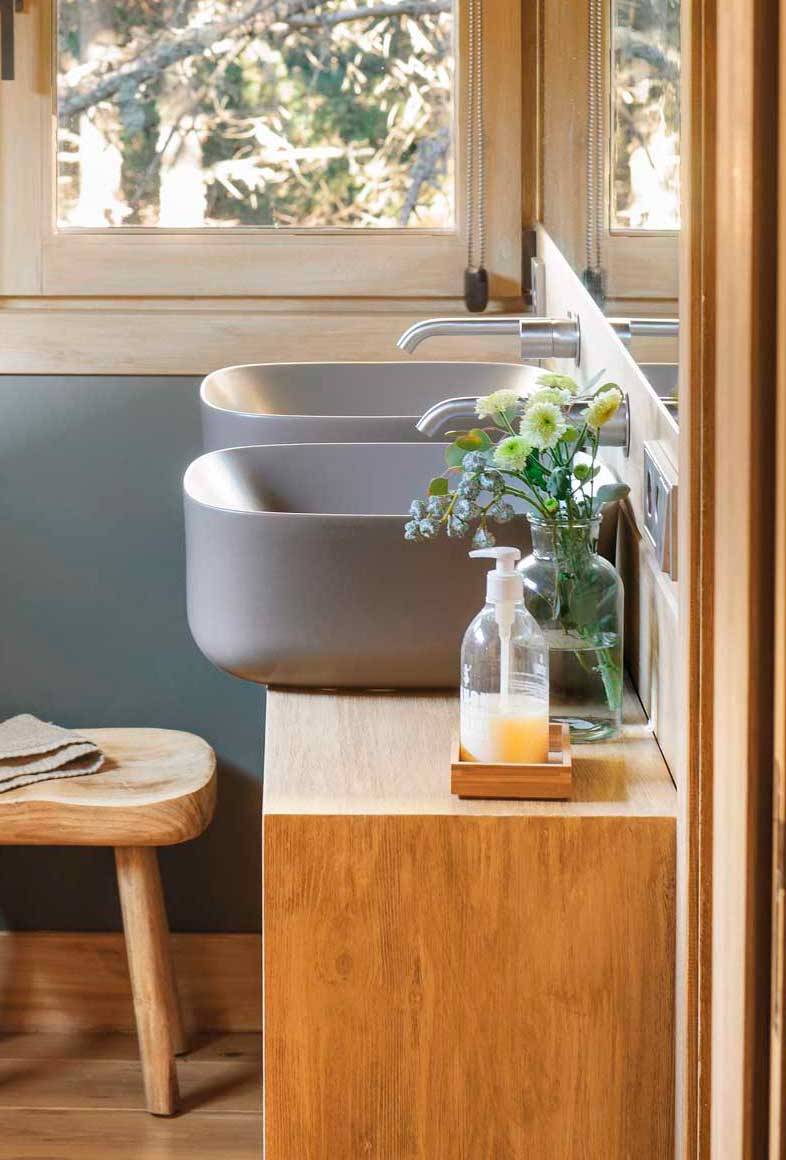 Baño moderno con lavamanos de color gris y muebles de madera.