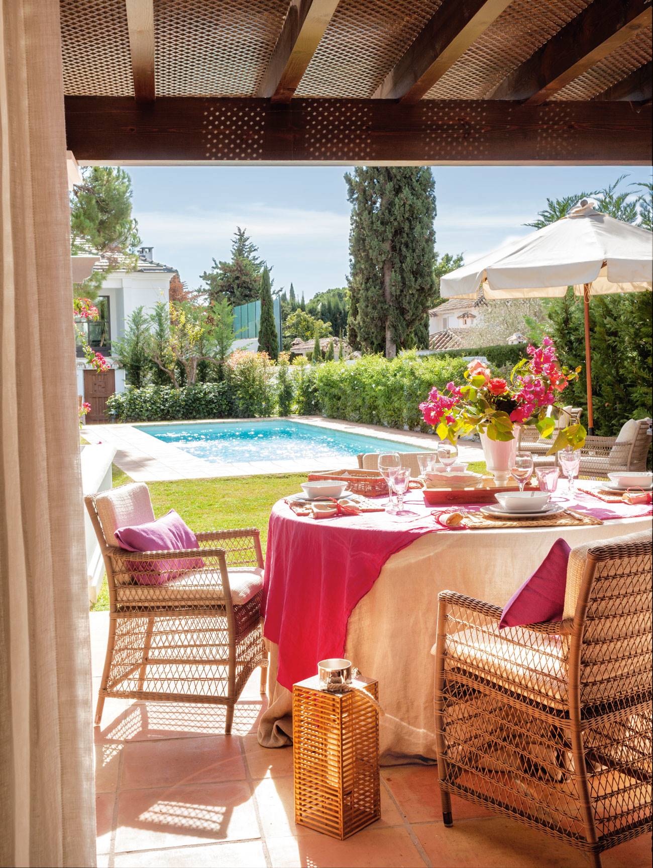 Comedor exterior junto a la piscina en tonos rosas y beige. 