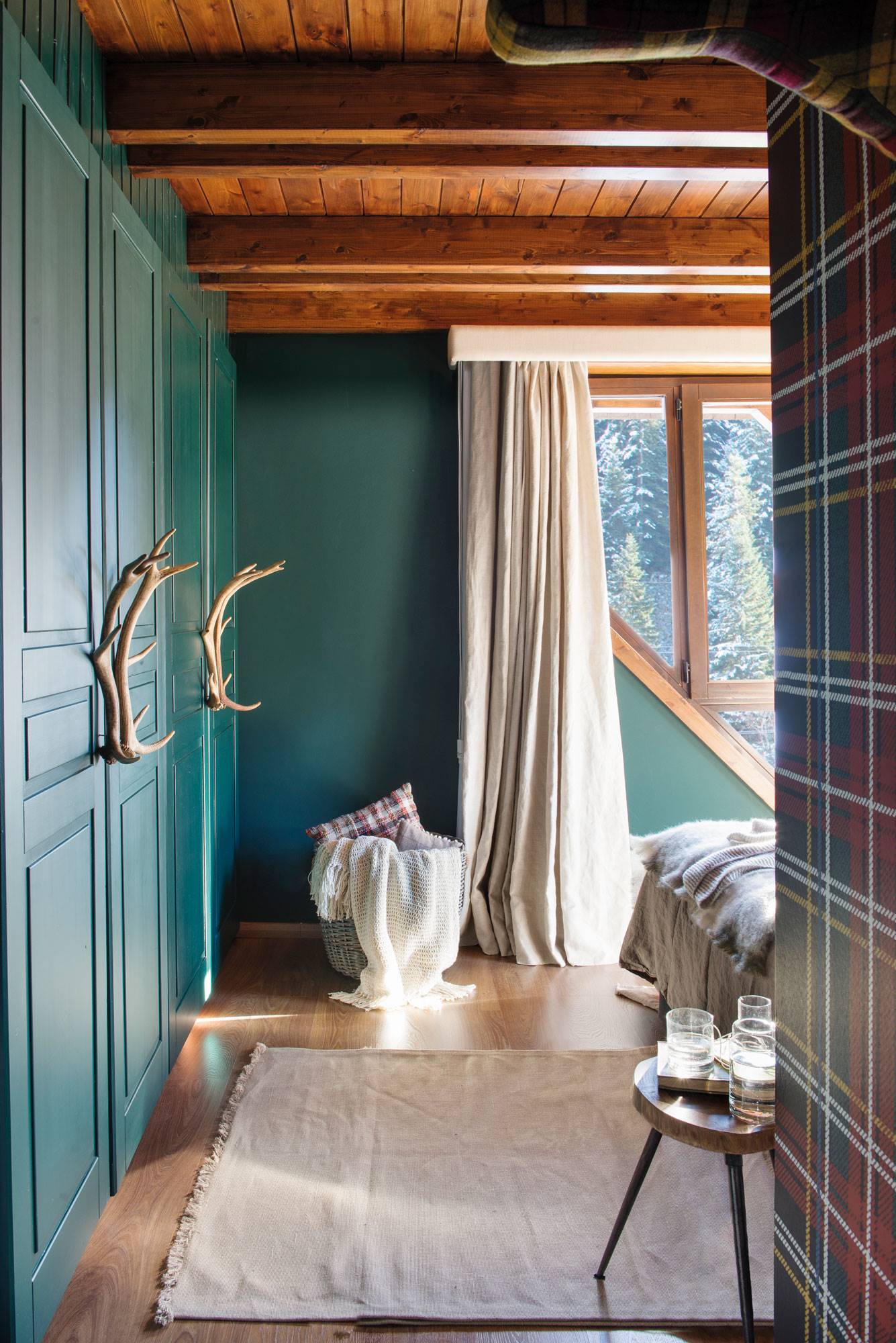 Dormitorio principal con armario pintado de color verde con unas astas como tirador.