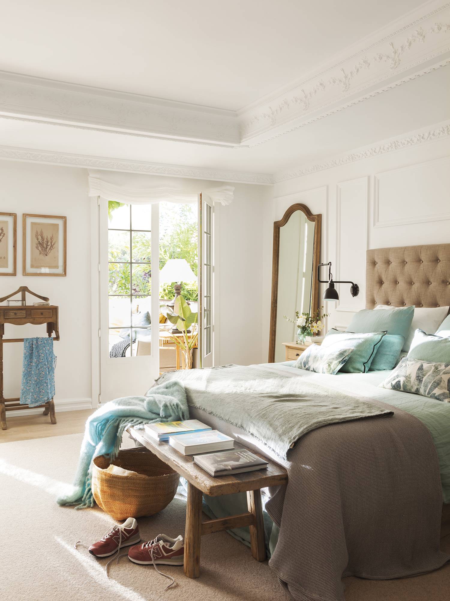 Dormitorio clásico con cabecero tapizado y molduras en la pared. 
