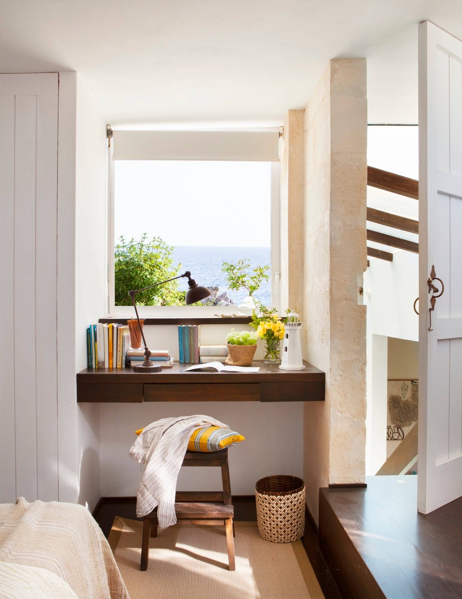 Dormitorio veraniego con un pequeño escritorio con vistas al mar. 