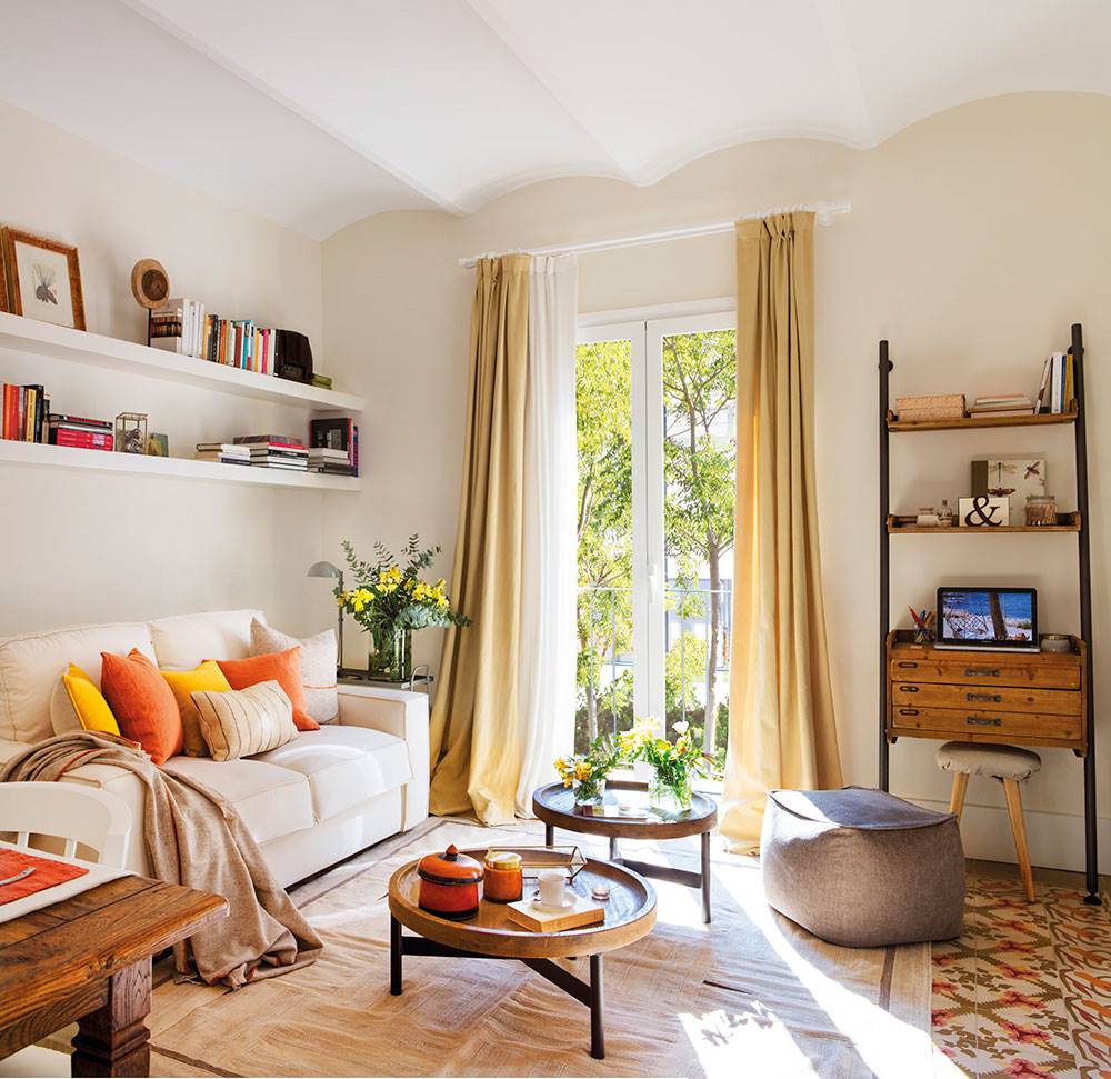 Salón pequeño con paredes en beige claro, sof�� blanco y suelos hidráulicos. 