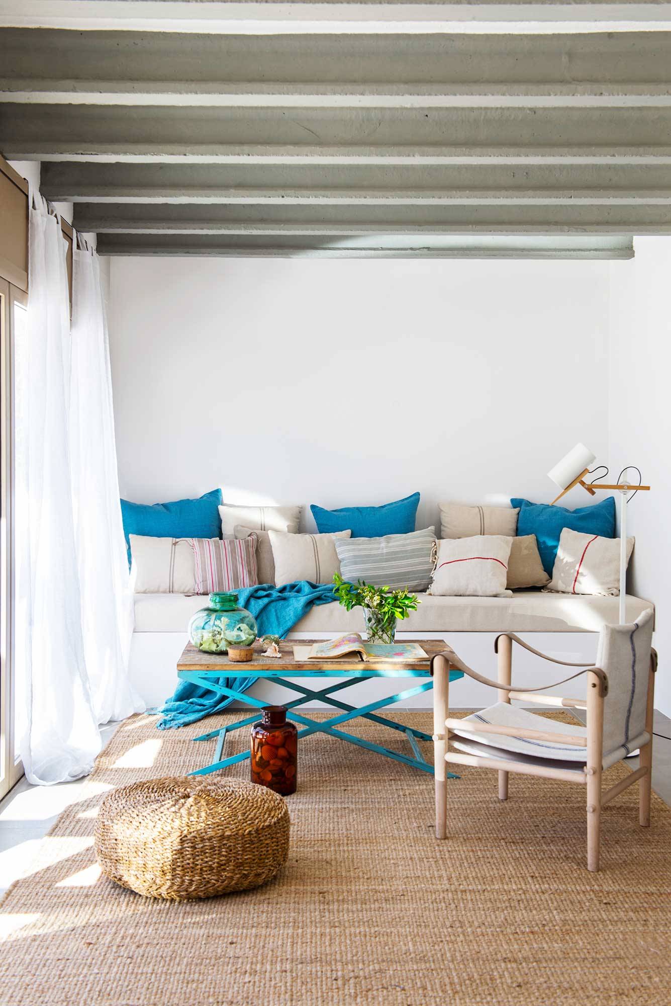 Salón con paredes y sofá blanco con cojines azules. 