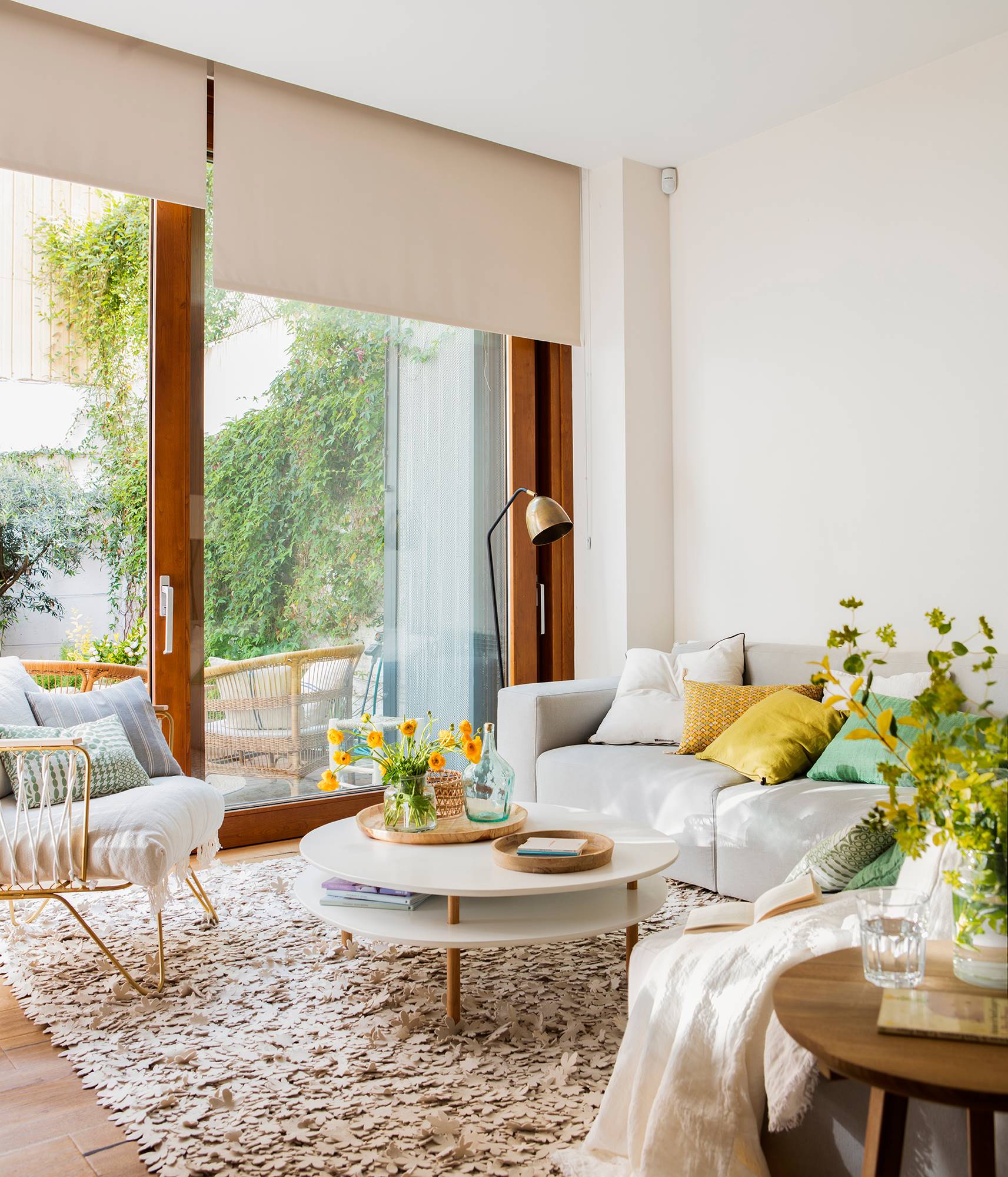 Salón pequeño blanco con ventanal al jardín con butaca y sofá. 