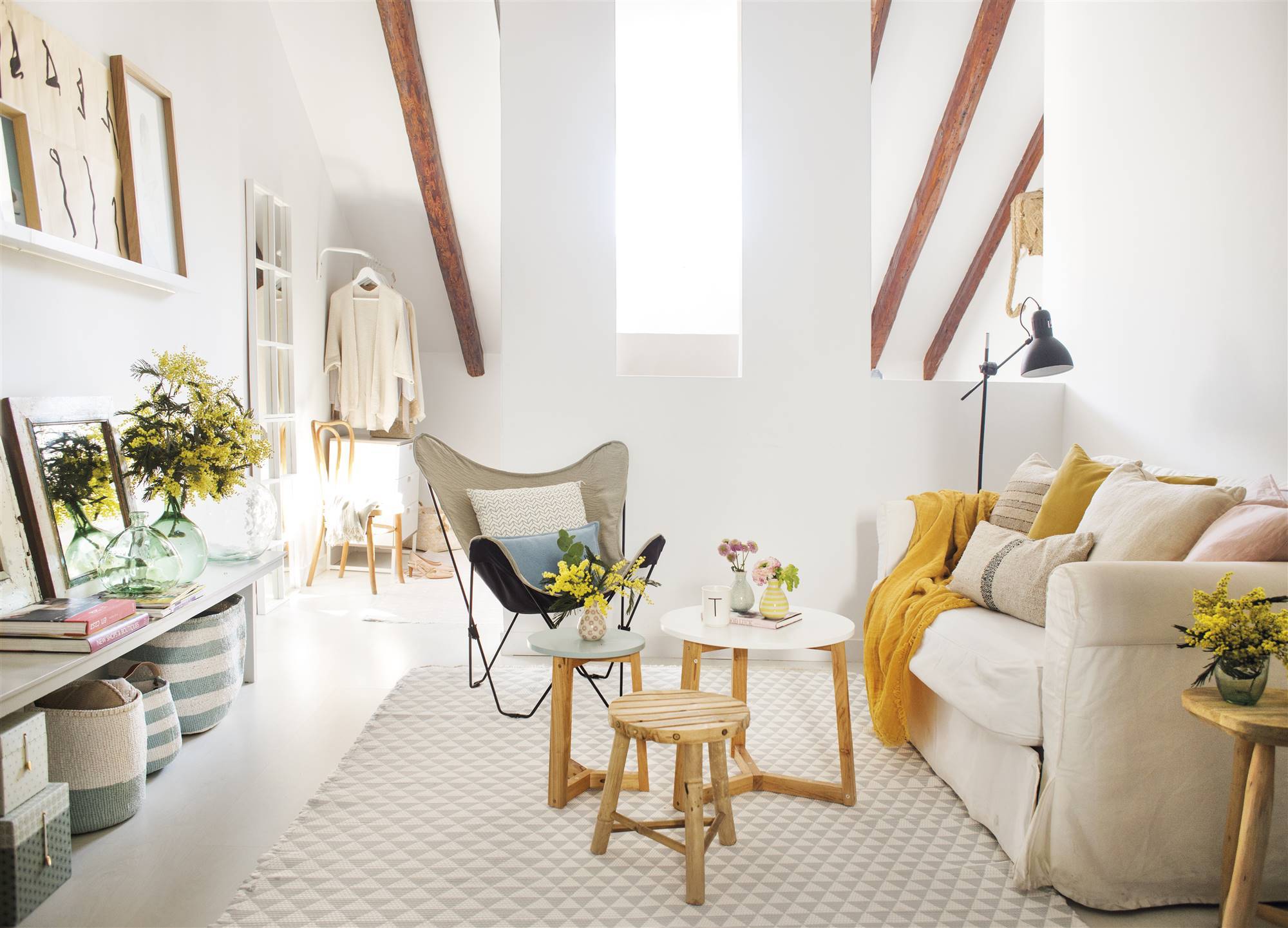 Salón pequeño en blanco con mesas de madera y detalles decorativos en amarillo. 