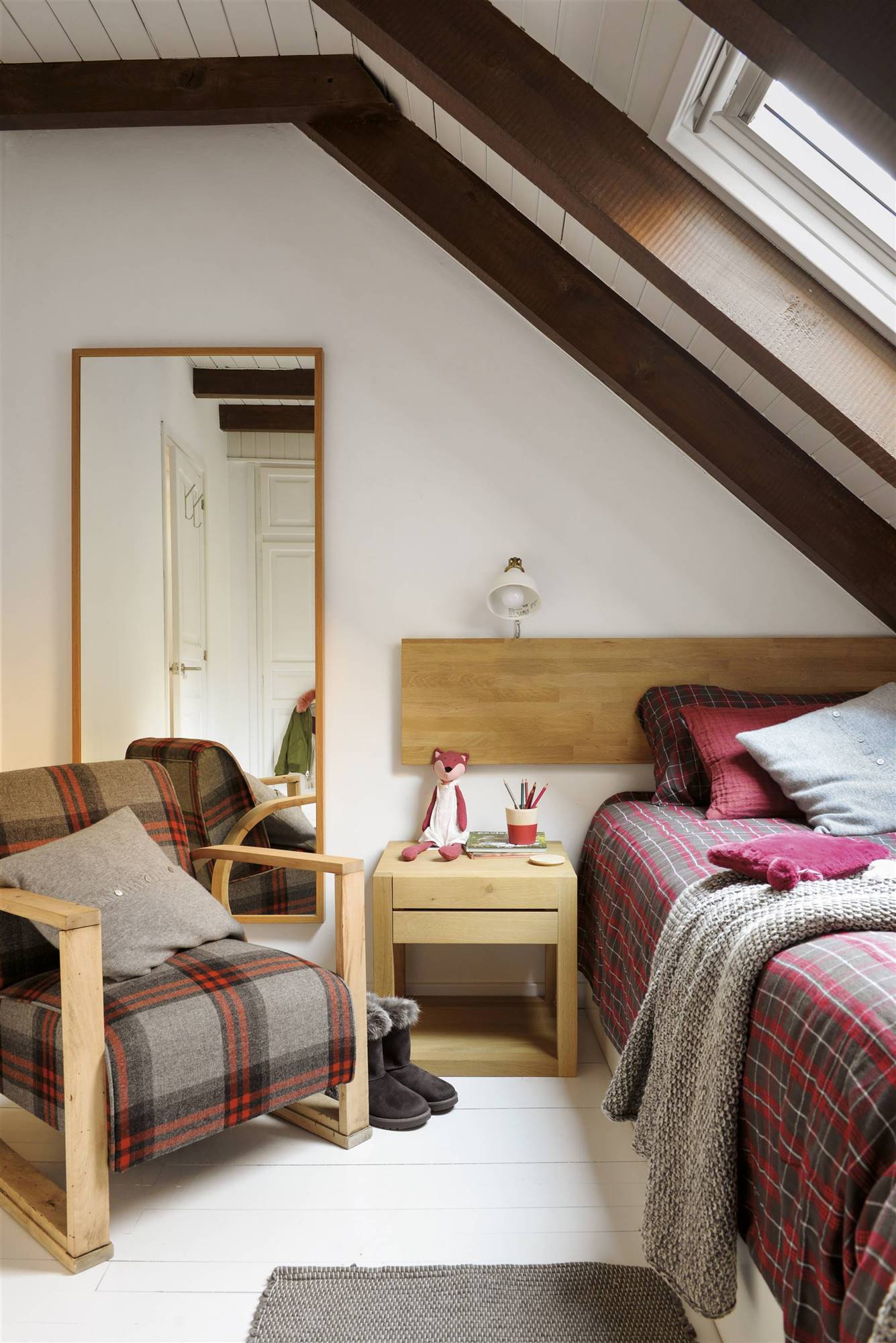 Dormitorio juvenil con cabecero de madera y ropa de cama de cuadros. 
