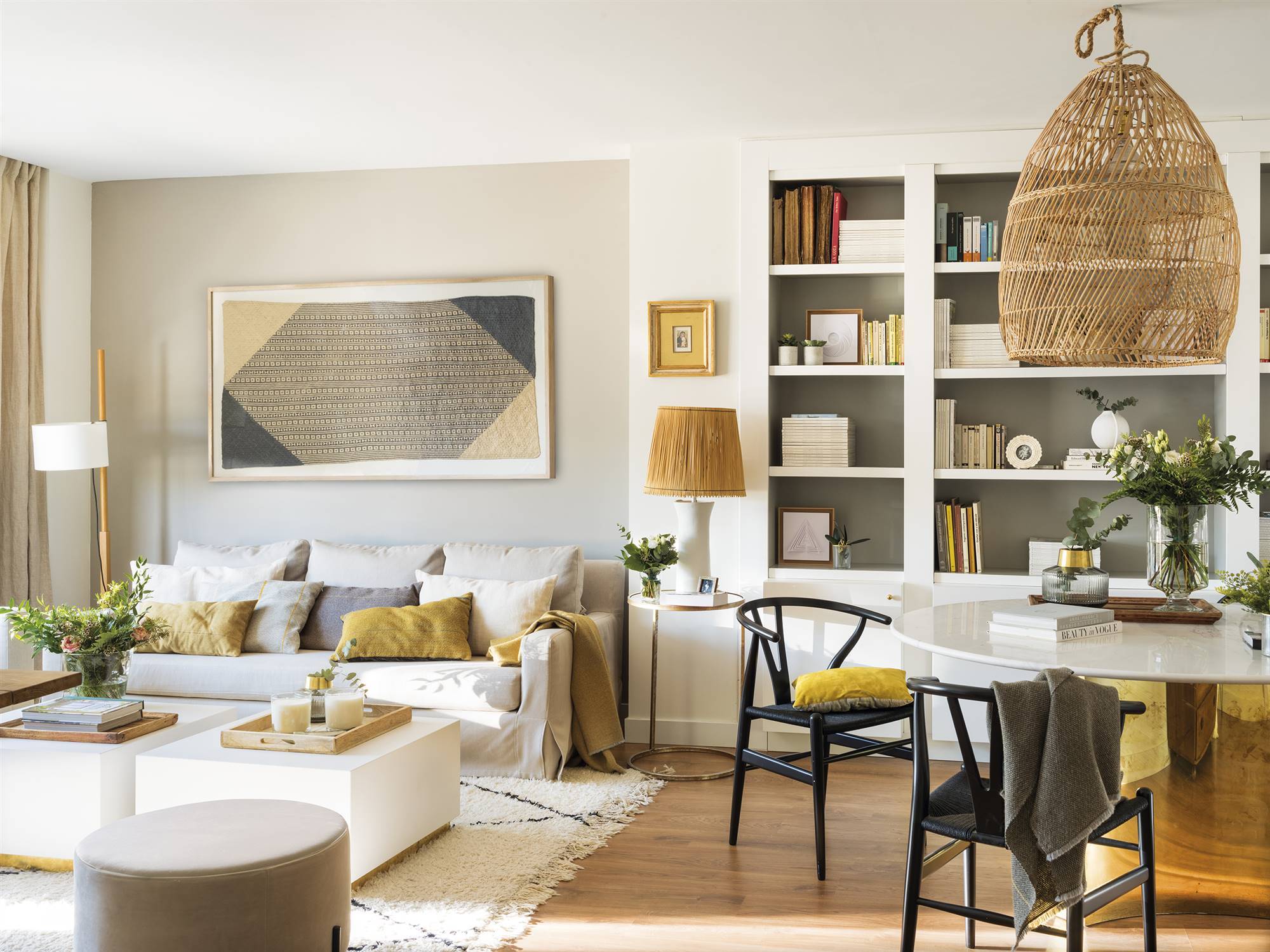 Salón con sofá blanco, comedor moderno, librería y toques de color mostaza.