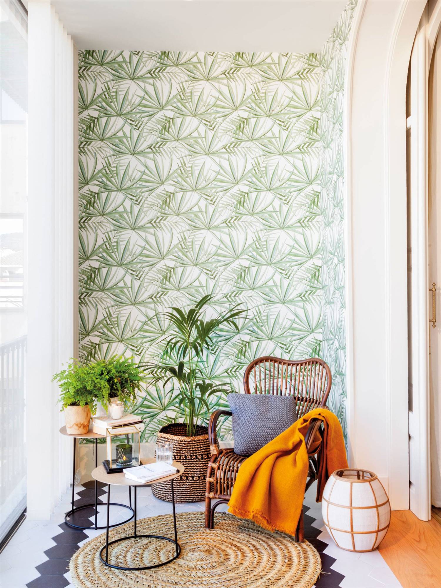 Galería con butaca de fibras y pared con papel pintado botánico.