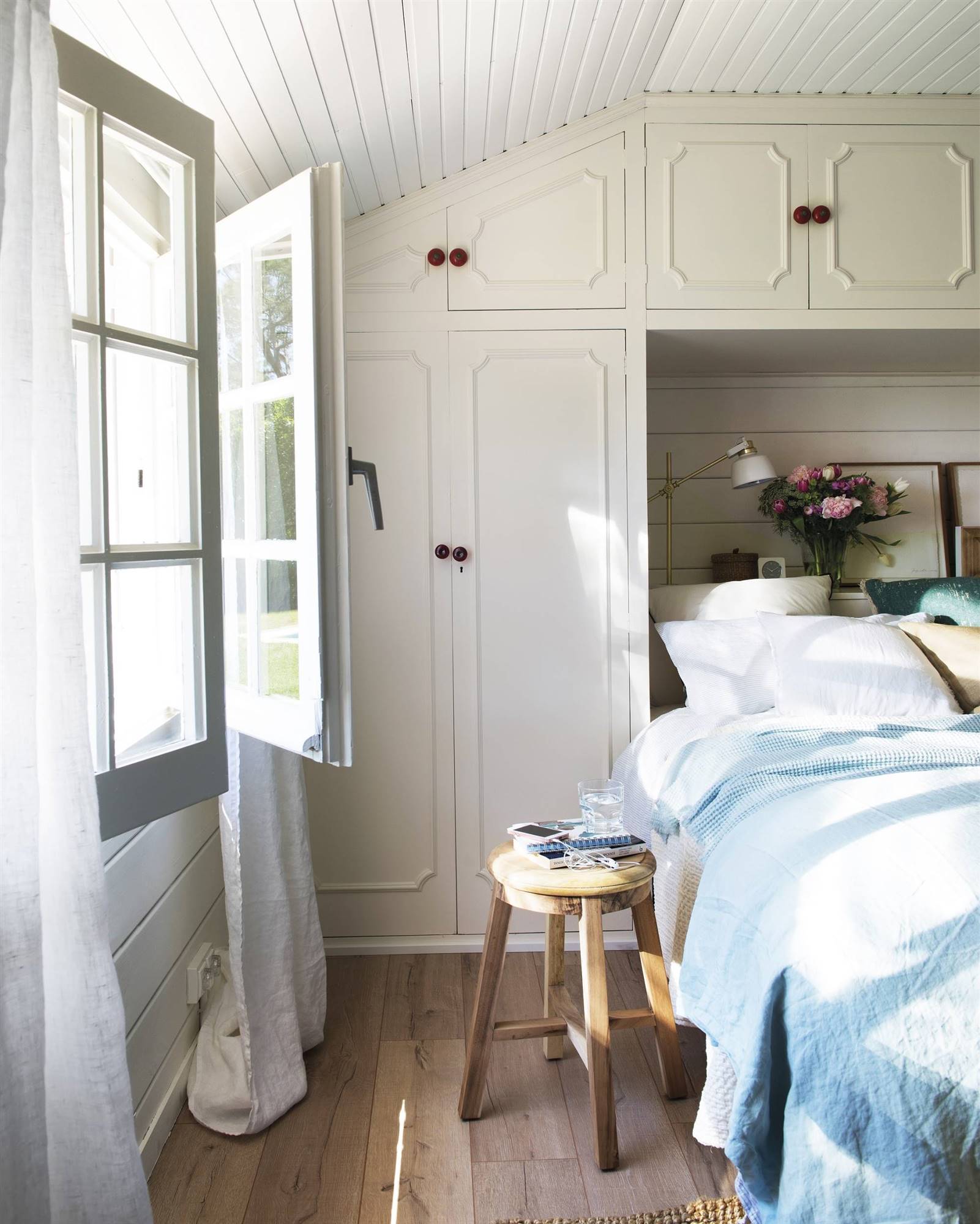 Dormitorio con armario a medida de color blanco que rodea el cabecero.