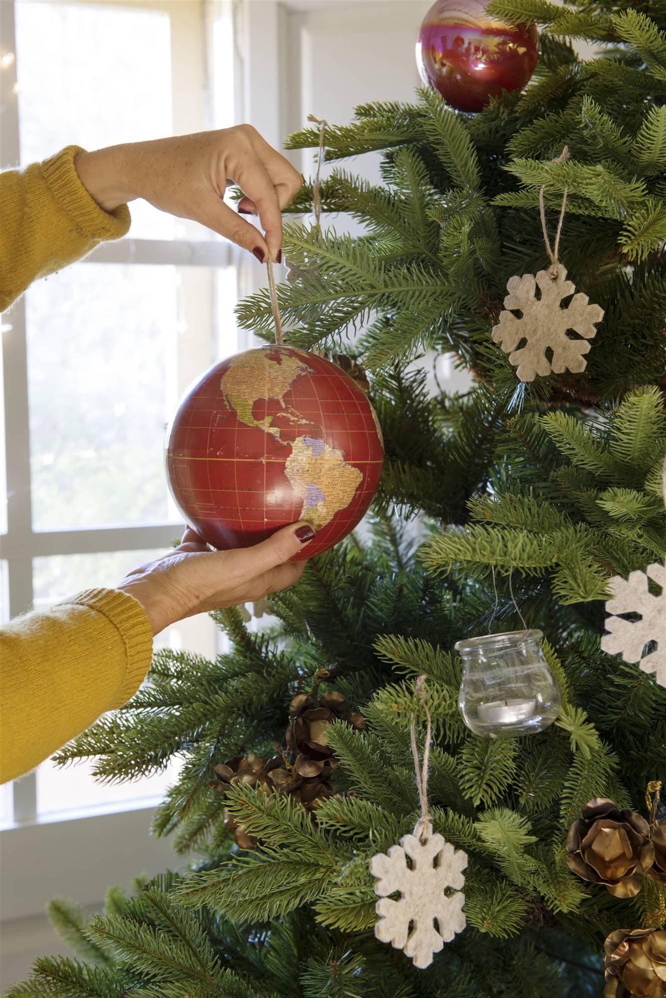 Árbol de Navidad decorado con un adorno del globo del mundo.
