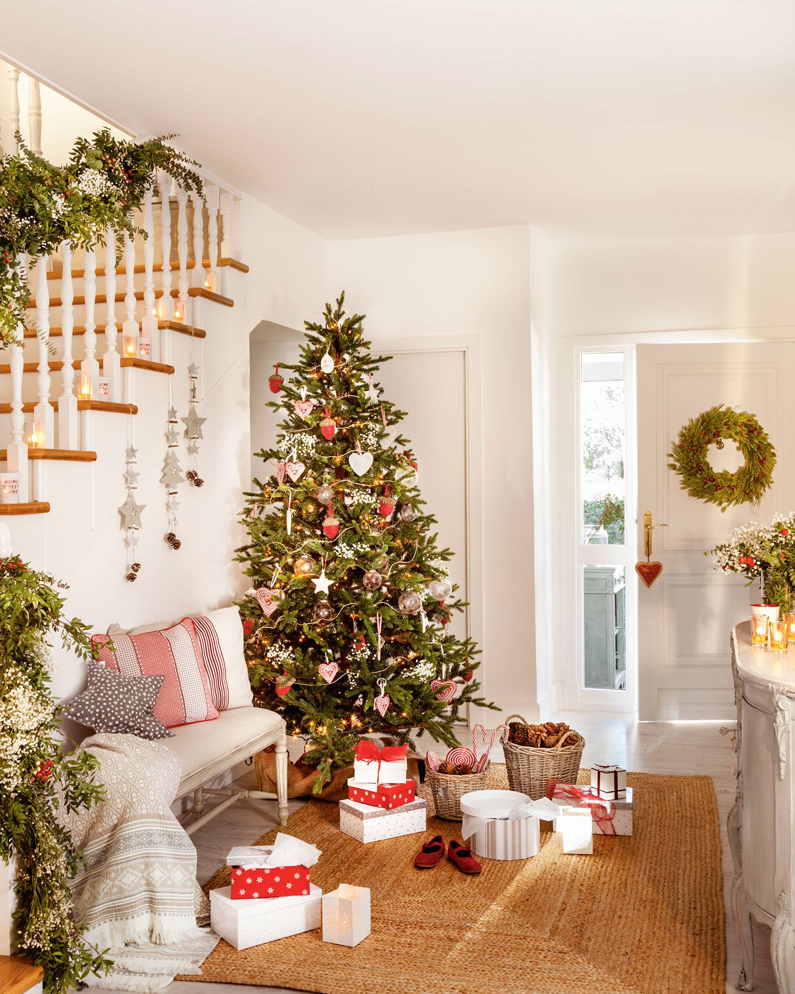recibidor blanco con escaleras y árbol de Navidad con adornos rojos