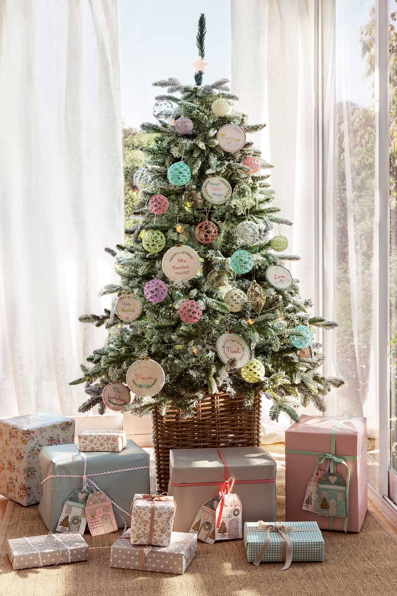 Salón con árbol de Navidad con adornos de ganchillo DIY y regalos bajo el árbol con tarjetas de patchwork. 