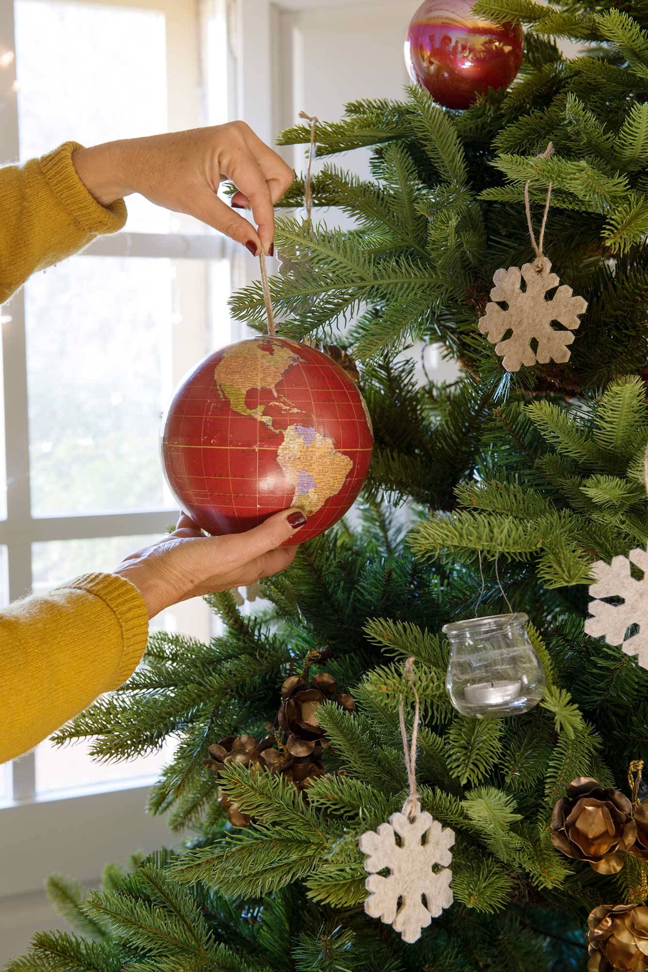Árbol de Navidad decorado con bolas mapamundi, velas y copos de fieltro.