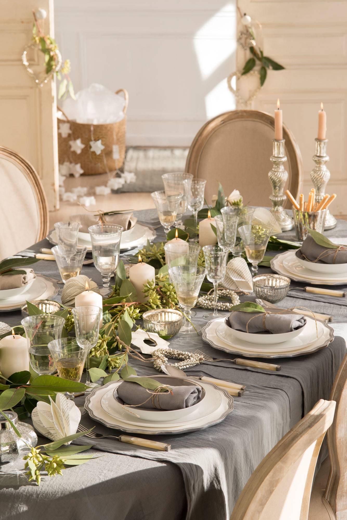 Mesa de Navidad con mantel gris y guirnaldas naturales en el centro de la mesa.