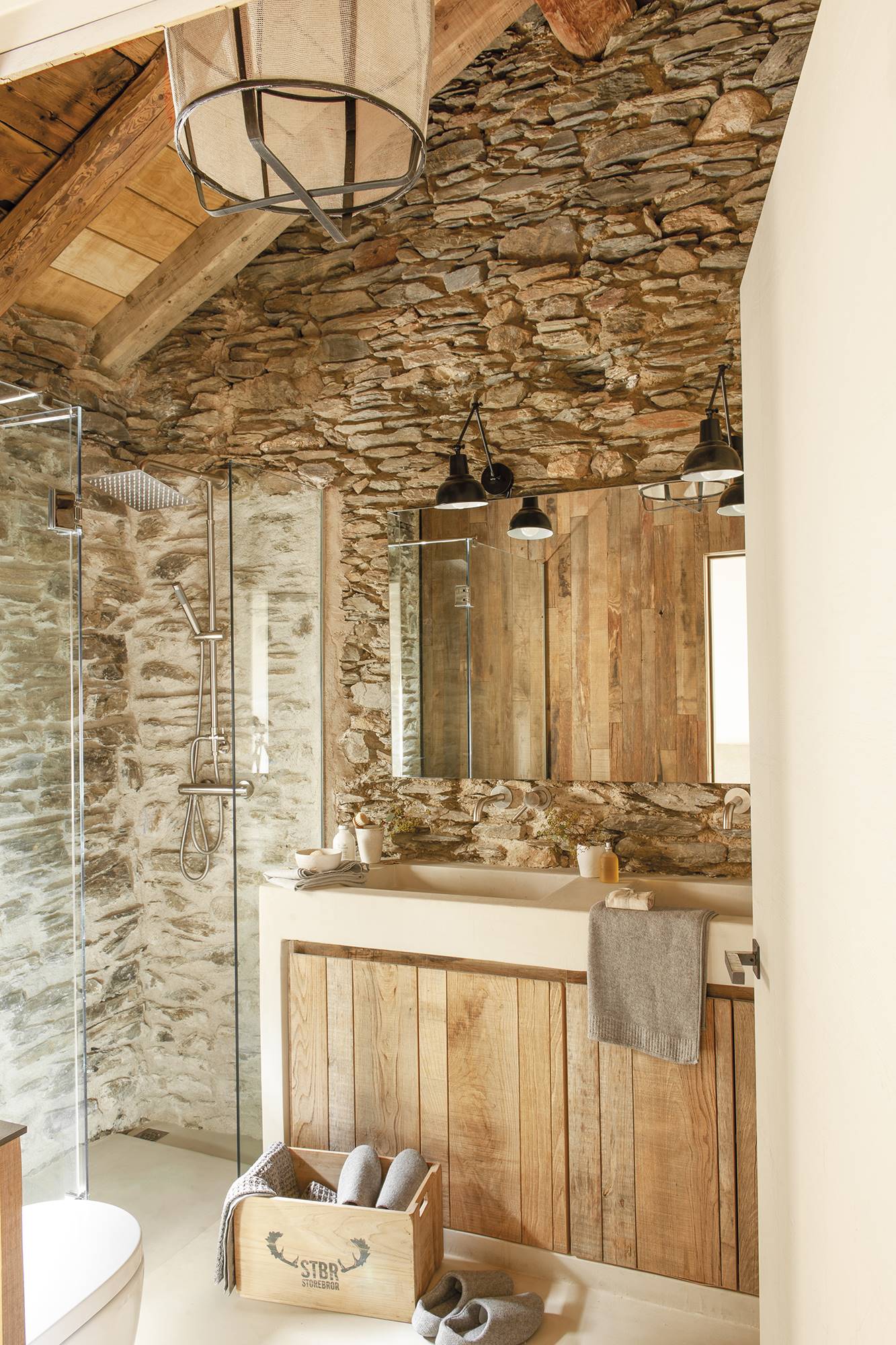 Baño rústico con paredes de piedra y mueble de baño de madera