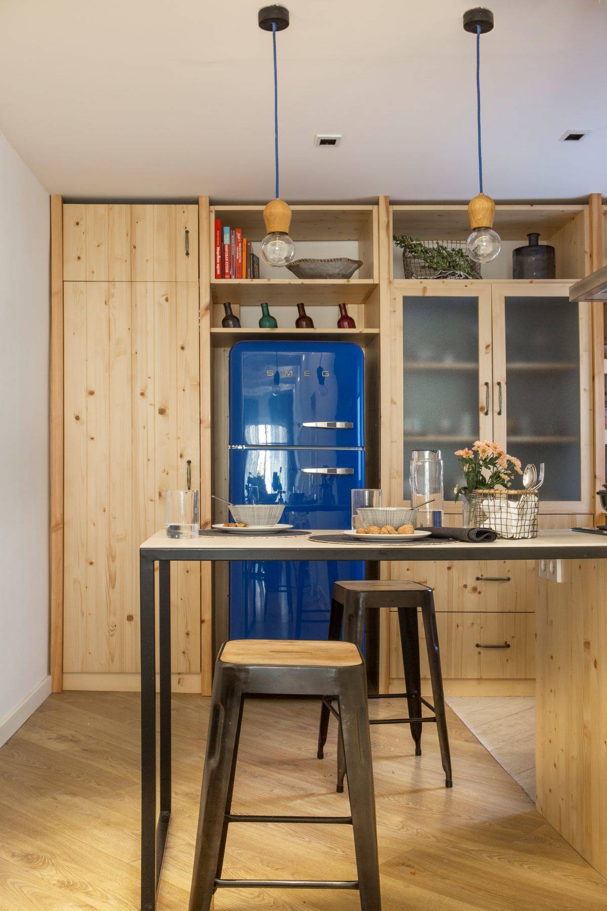 Small wooden kitchen with blue fridge. 