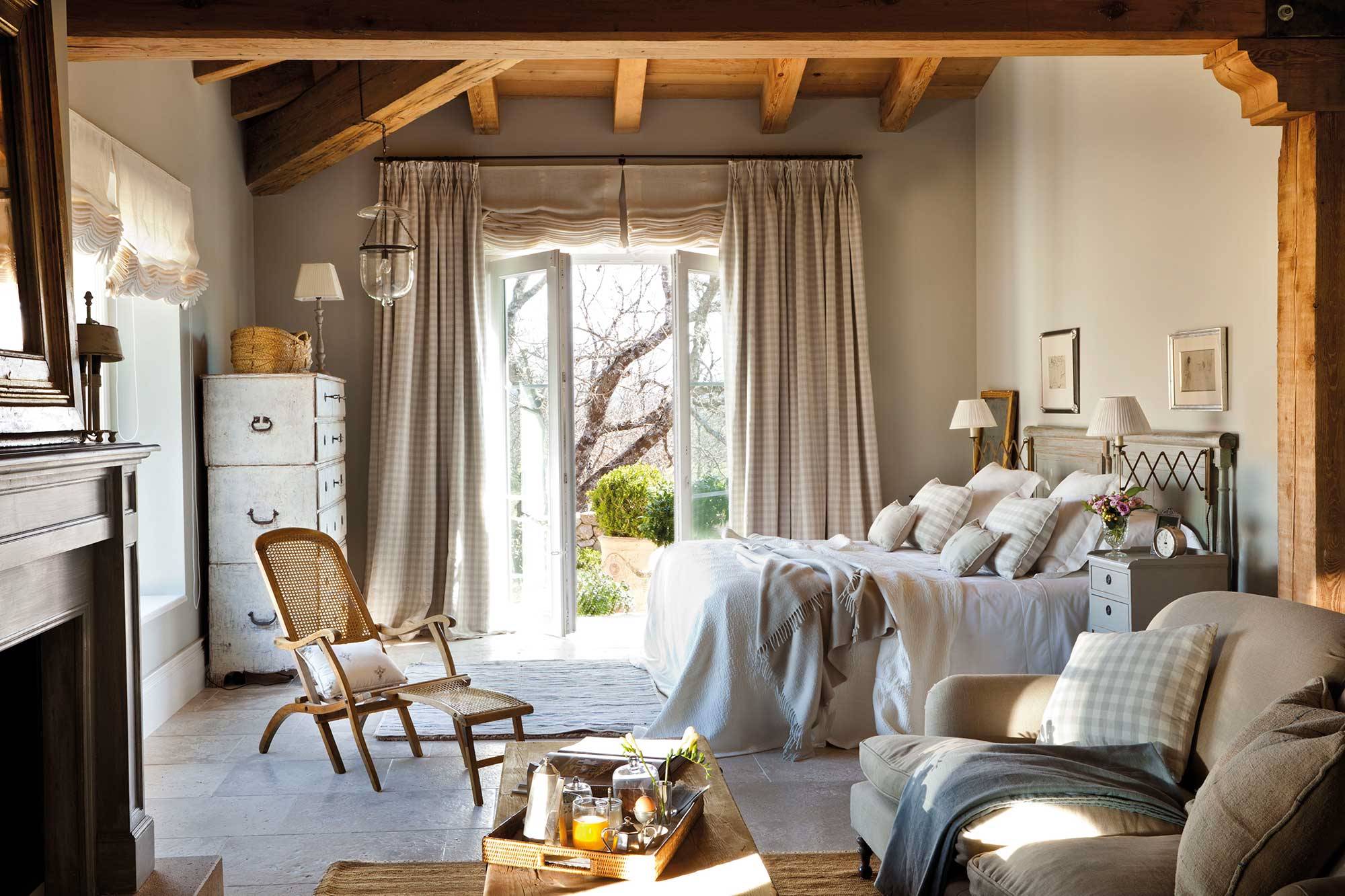 Dormitorio con vigas, ropa de cama y chimenea estilo vintage.