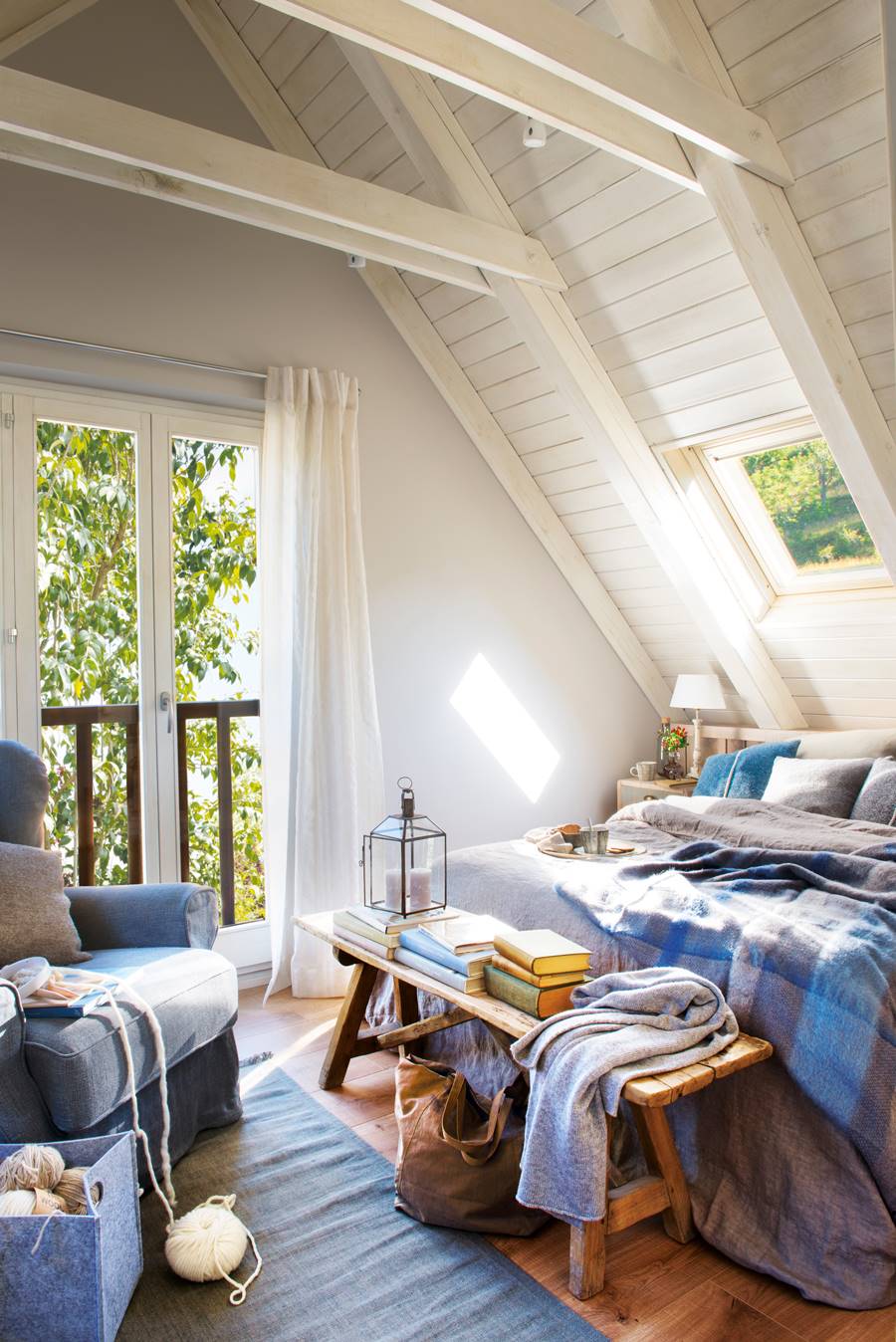 Dormitorio con vigas blancas y ropa de cama azul.