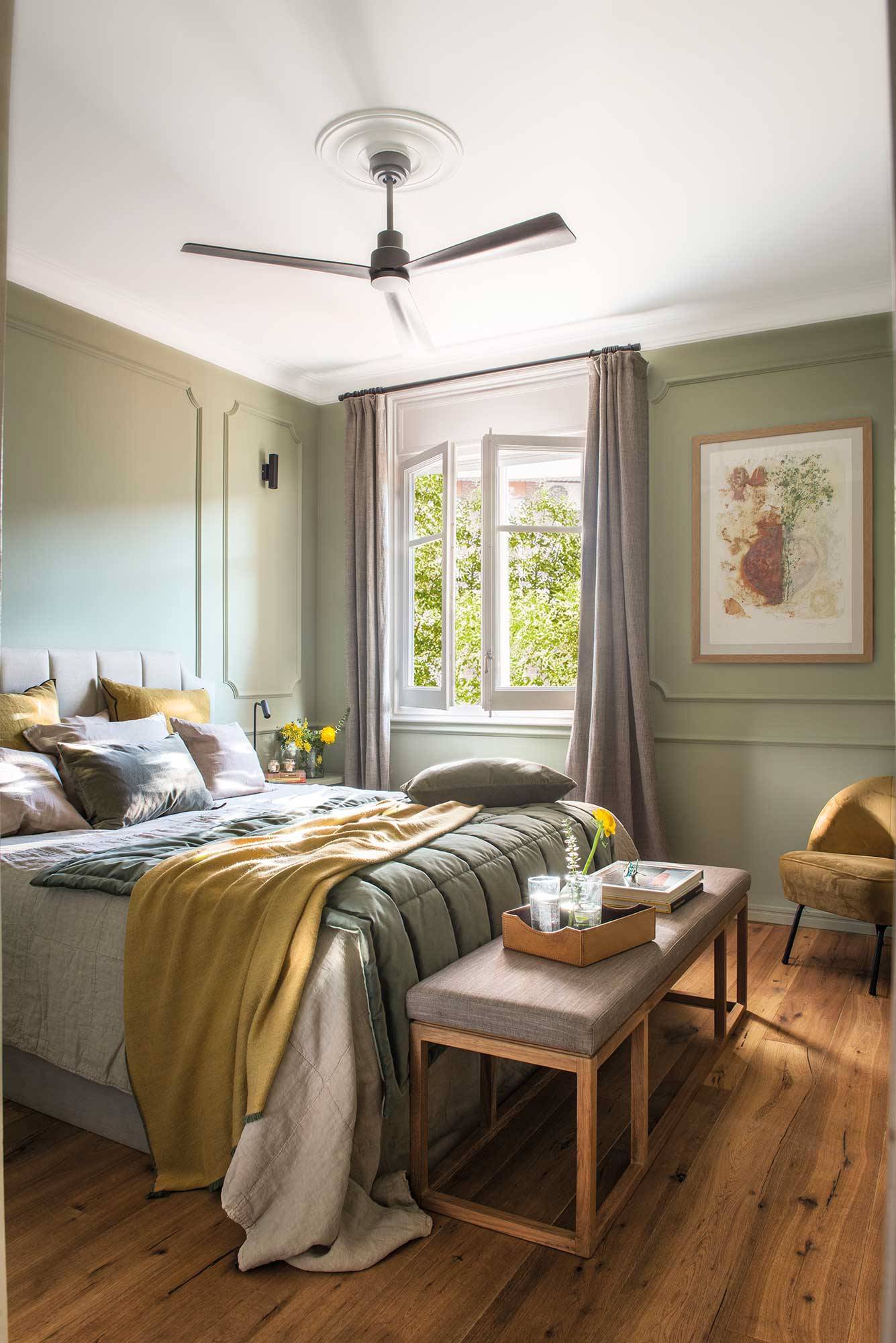 Dormitorio en color verde musgo con banco, ventilador y molduras.