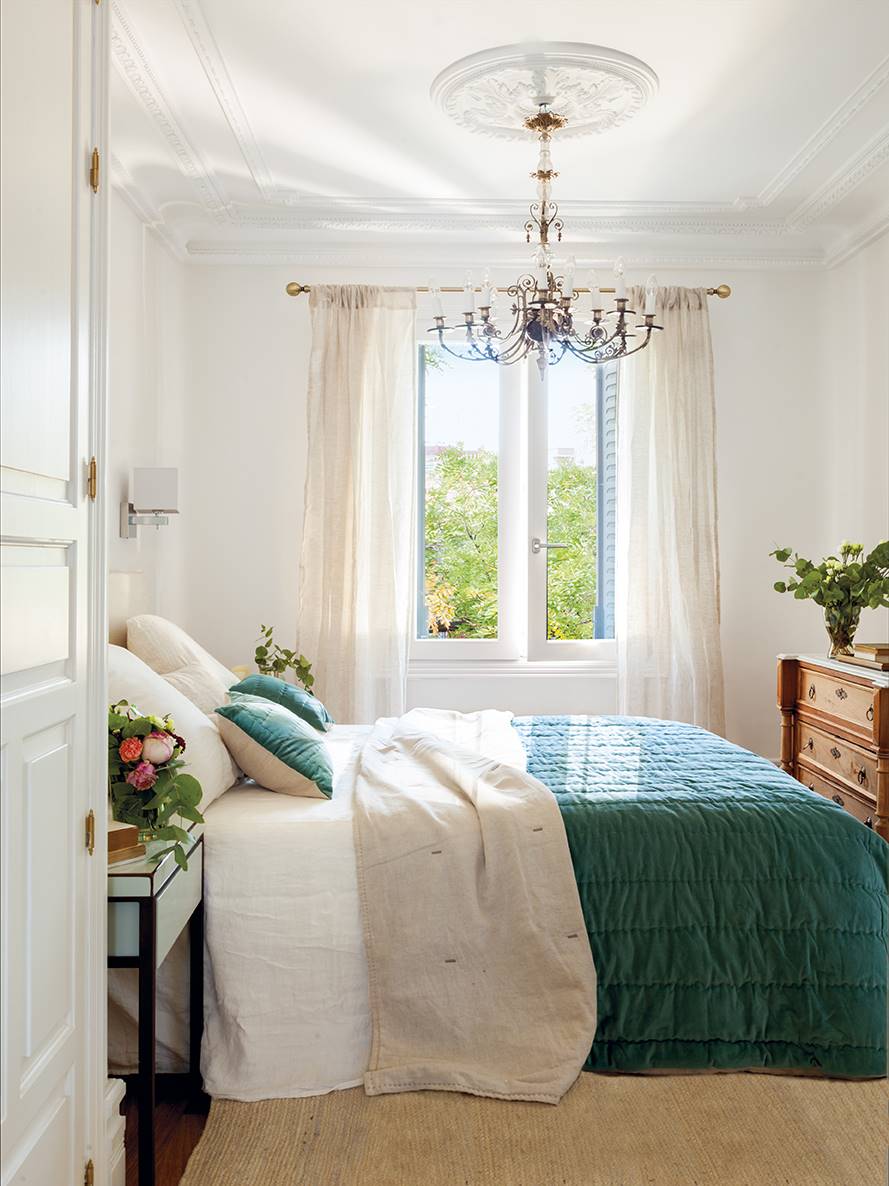 Dormitorio clásico con molduras y lámpara de araña. 