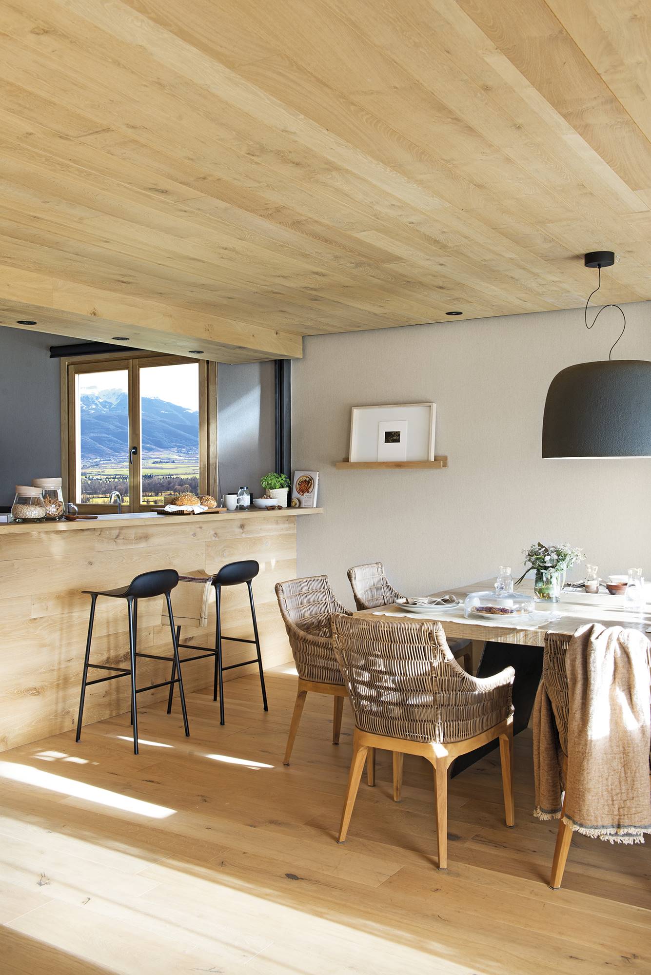 Comedor abierto a la cocina con barra de casa rústica de montaña. 