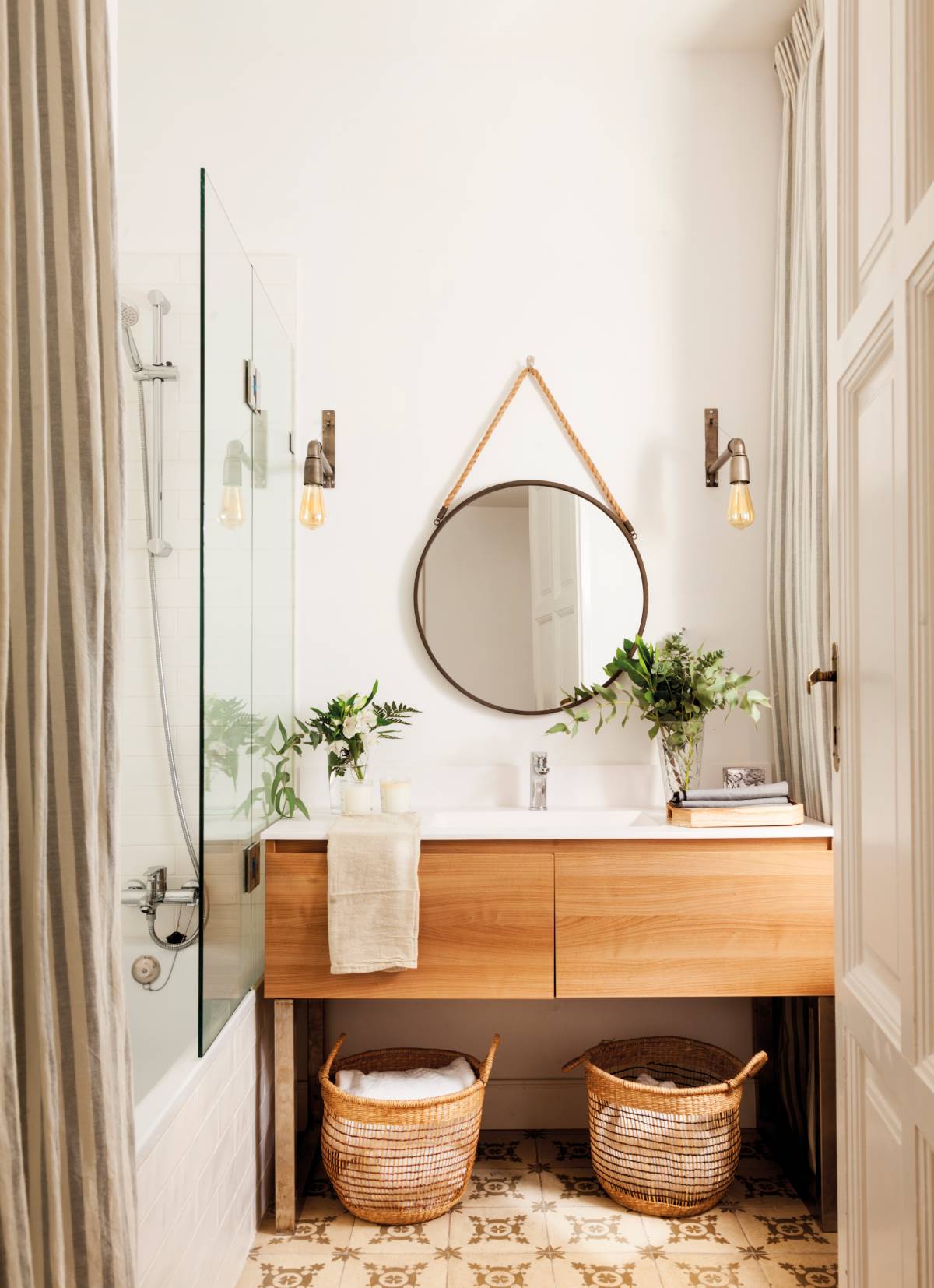 Baño pequeño moderno con mueble de madera y espejo redondo. 