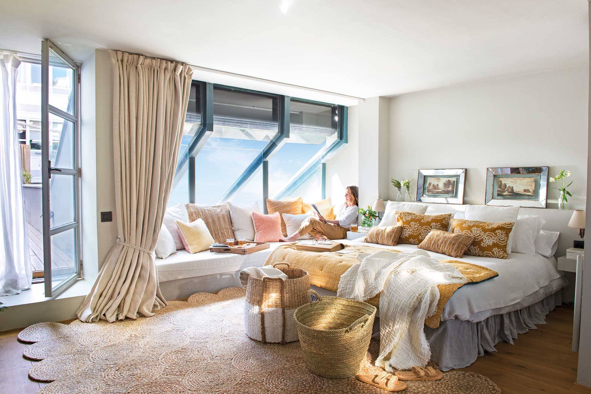 Dormitorio primaveral con banco bajo la ventana, cortinas largas en beige y cestas de fibra a los pies