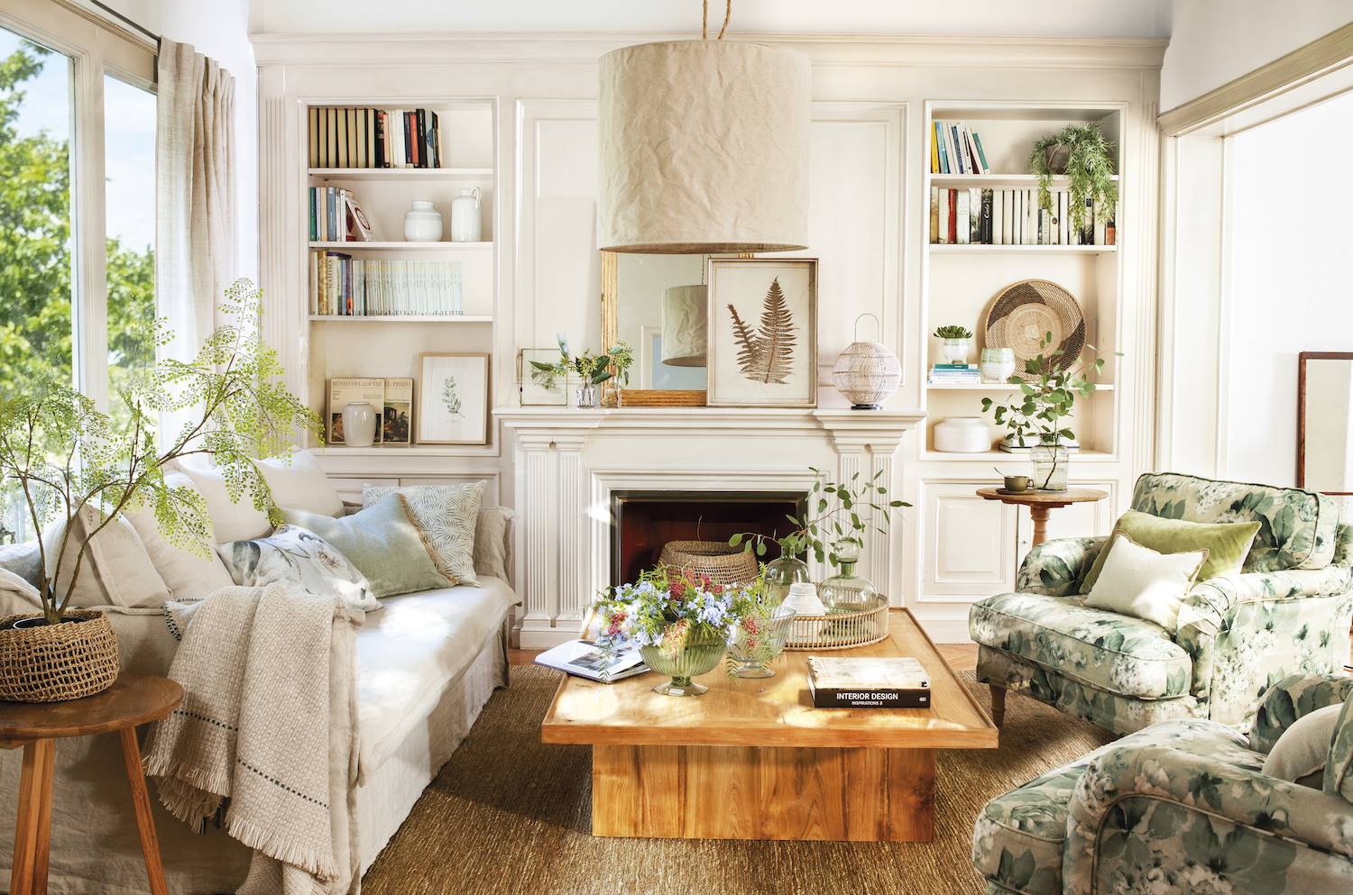 Salón moderno con butacas con estampados naturales, chimenea, librerías y sofá blanco.