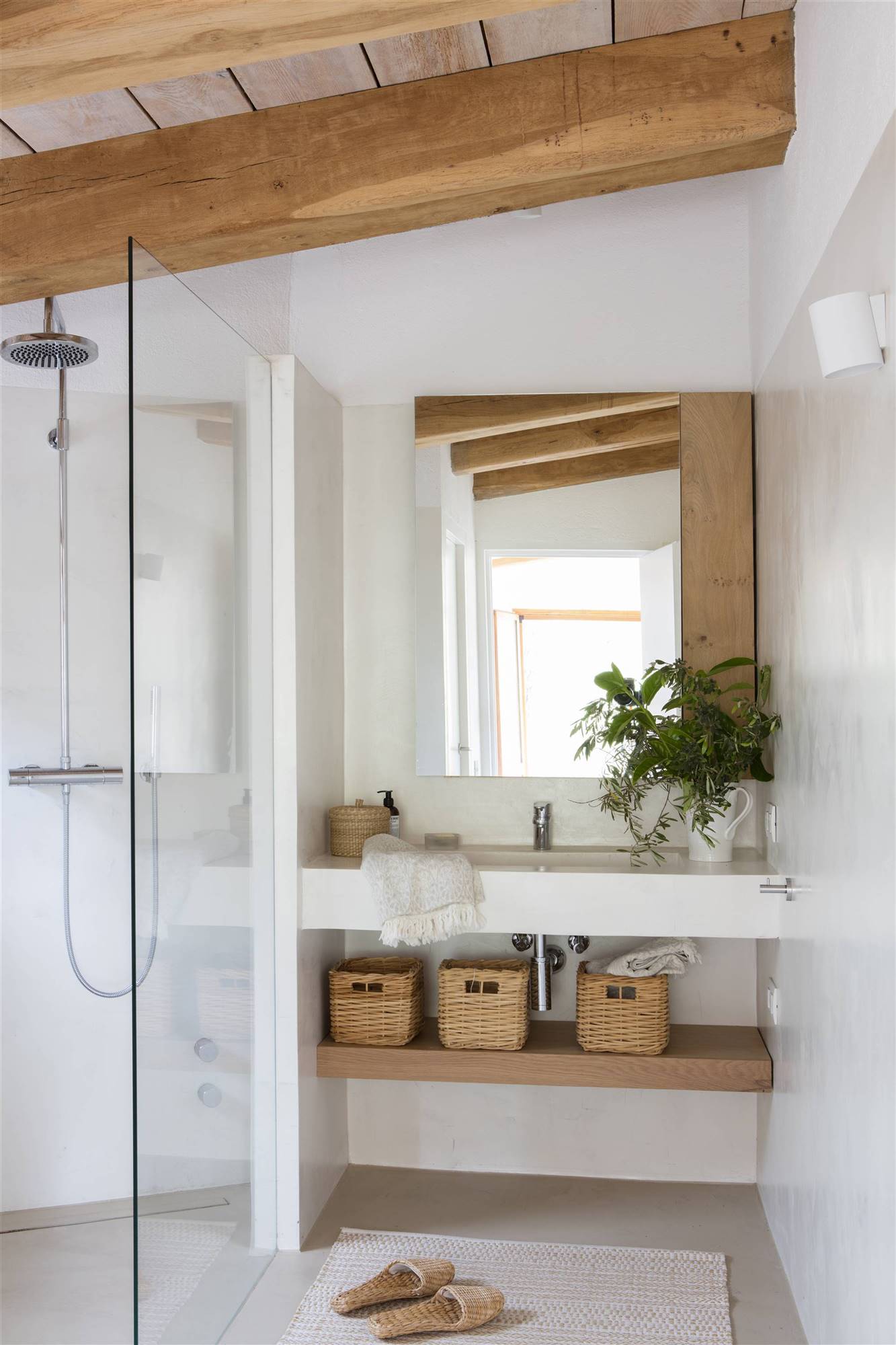 Reforma de baño con microcemento, espejo, estante de madera y ducha con mampara.