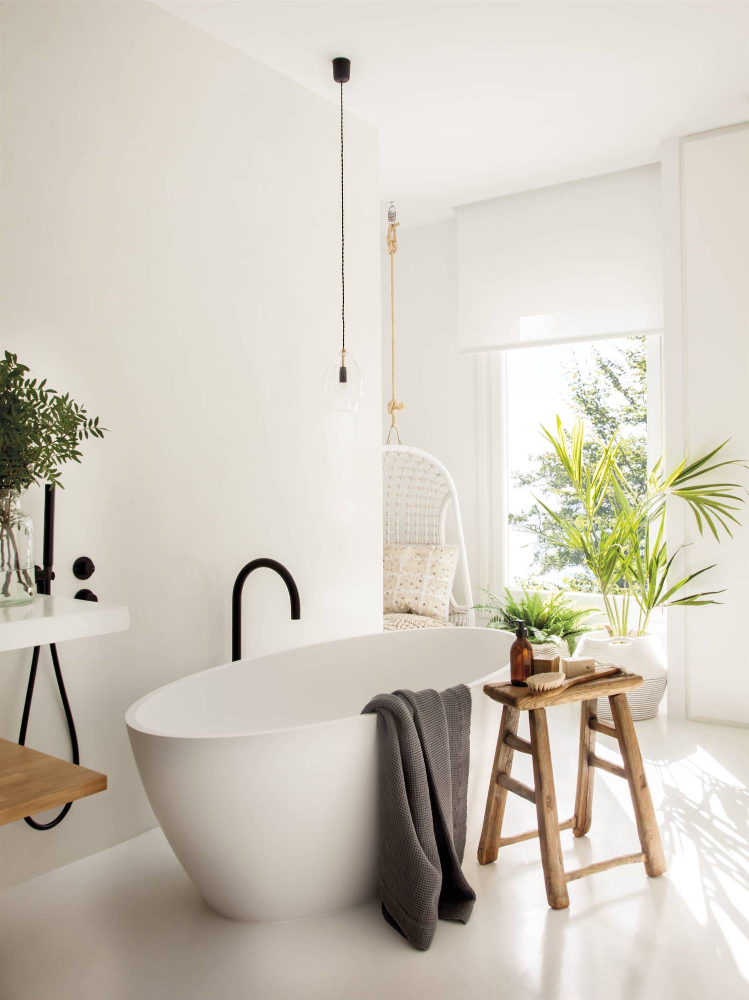 Reforma en baño ahora blanco con bañera exenta, taburete de madera y planta. 