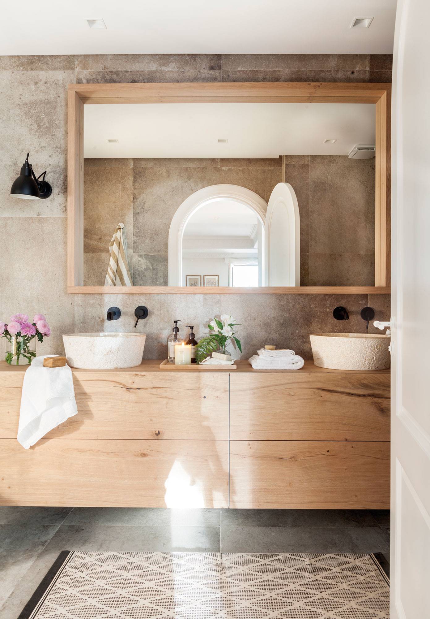 Baño con mueble volado de madera y espejo con marco de madera.