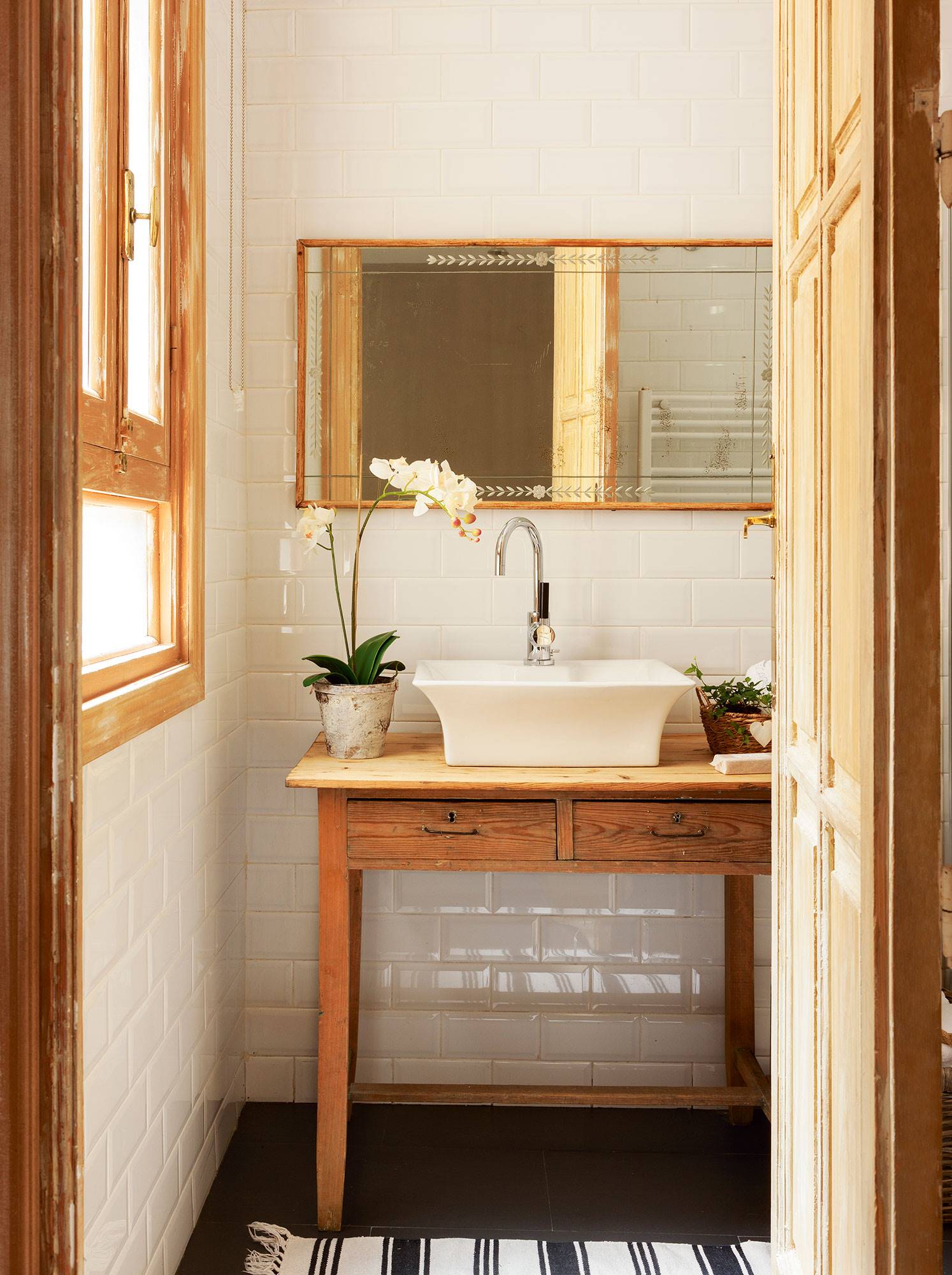 Baño clásico con espejo con marco de madera y planta.