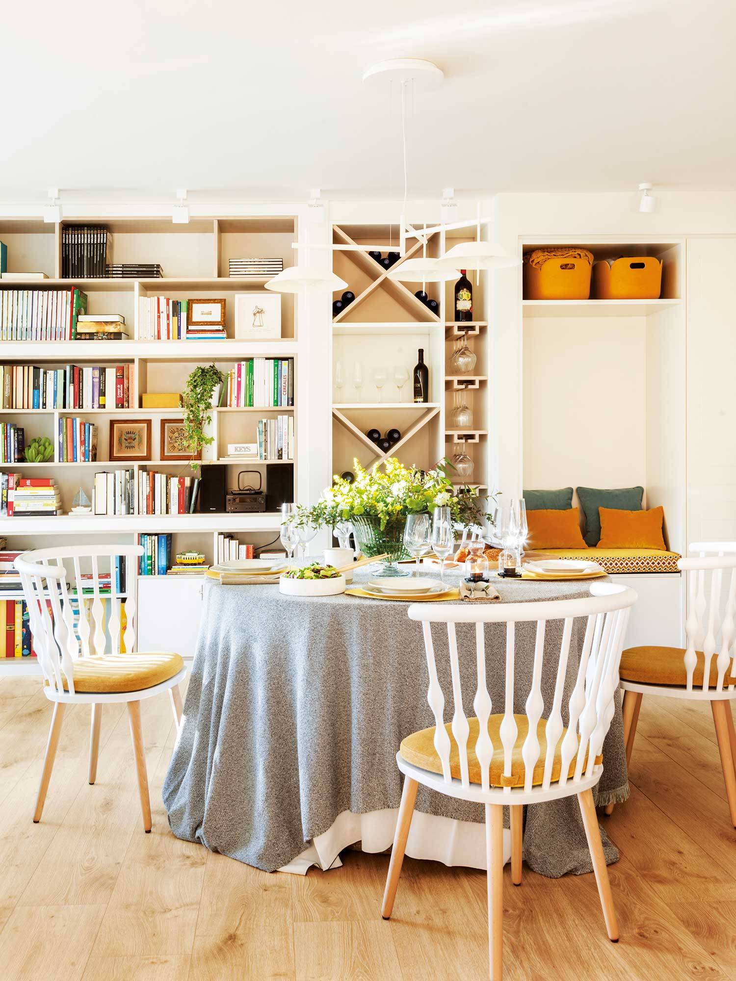 Comedor con mueble de pared a pared en blanco, mesa de comedor redonda y sillas de color blanco. 