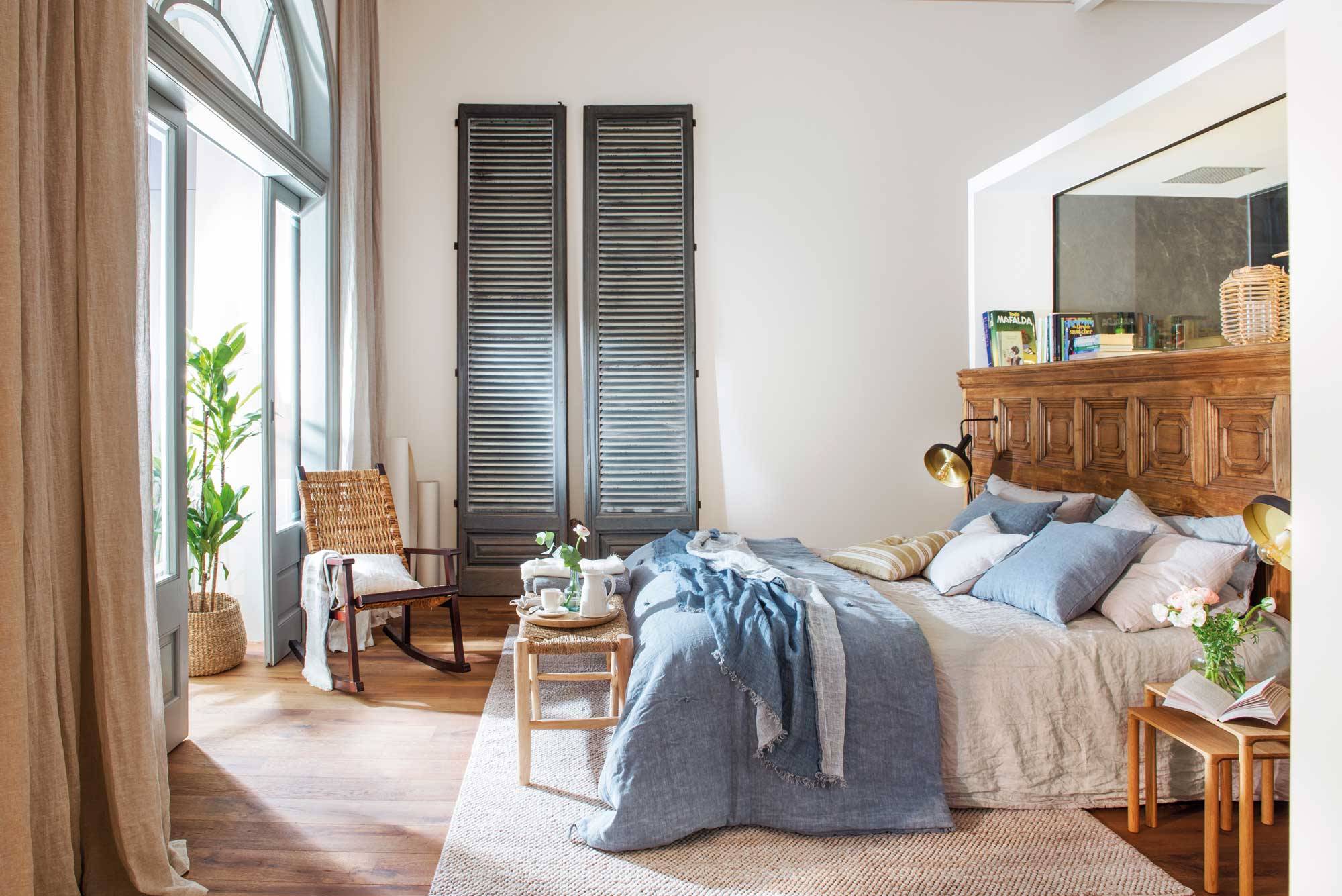 Dormitorio de verano con cabecero de madera y ropa de cama azul y blanca. 