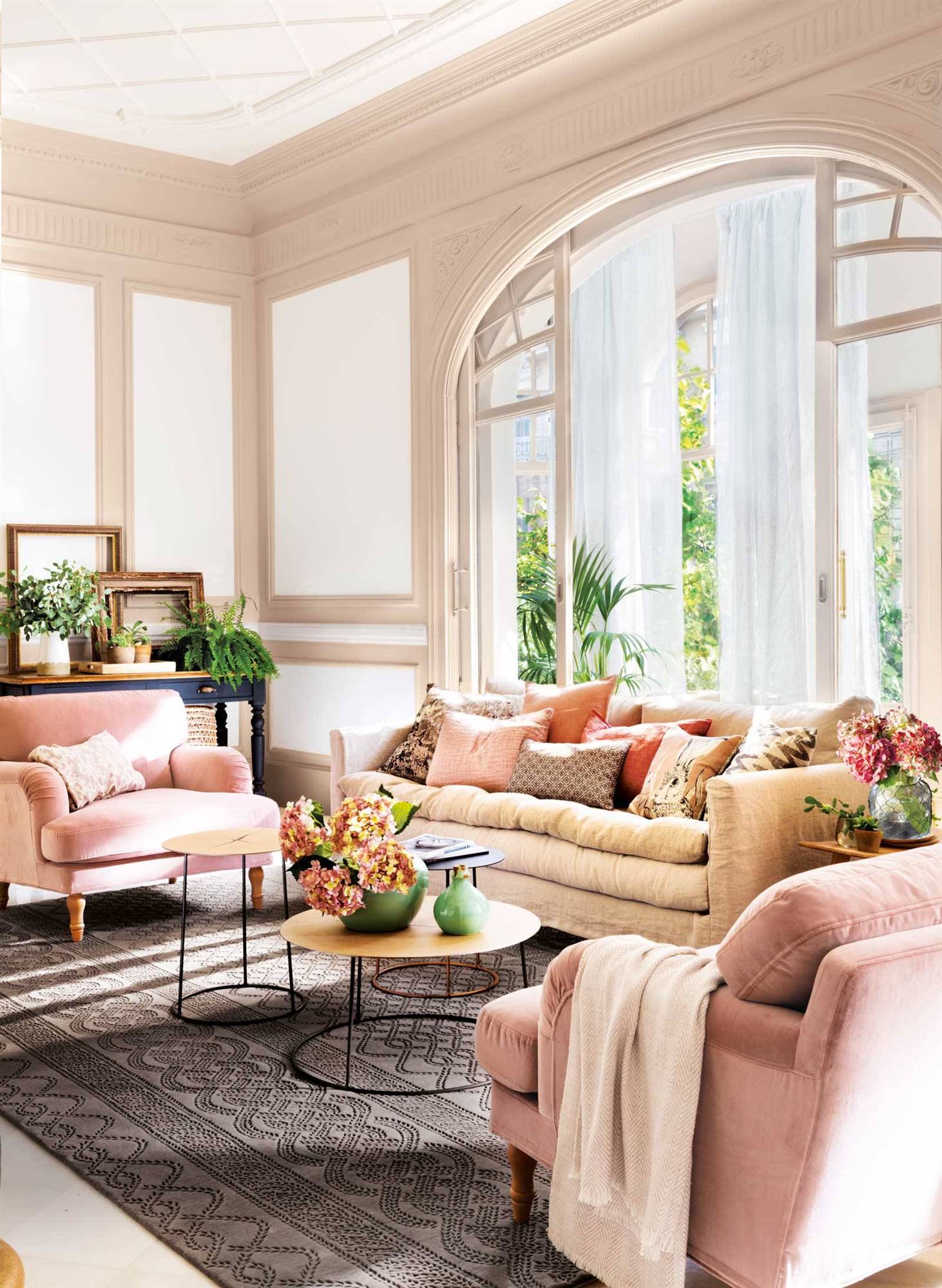 Combinación de sofá beige y butacas de color rosa en salón con molduras