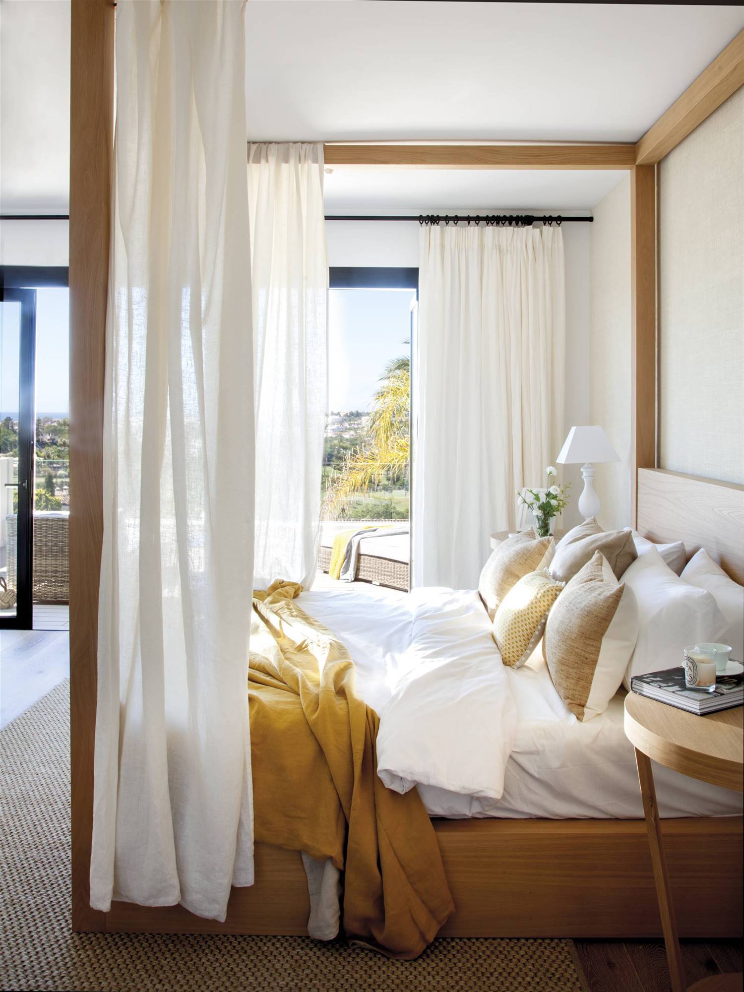 Dormitorio con cama con dosel de madera y ropa de cama blanca y mostaza.  